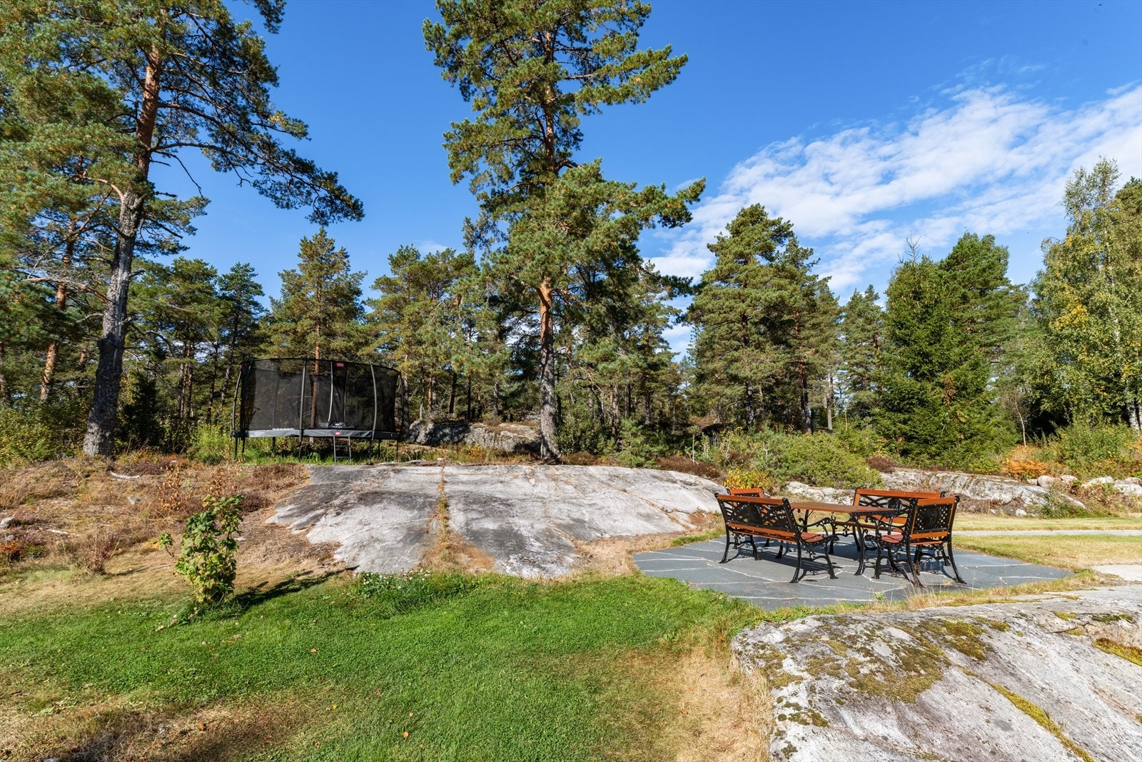 En sti belagt med granitt heller fører frem til et trivelig skiferbelagt dekke med klassiske smijernsmøbler. Møbler kan etter avtale med selger følge eiendommen. Galleribilde