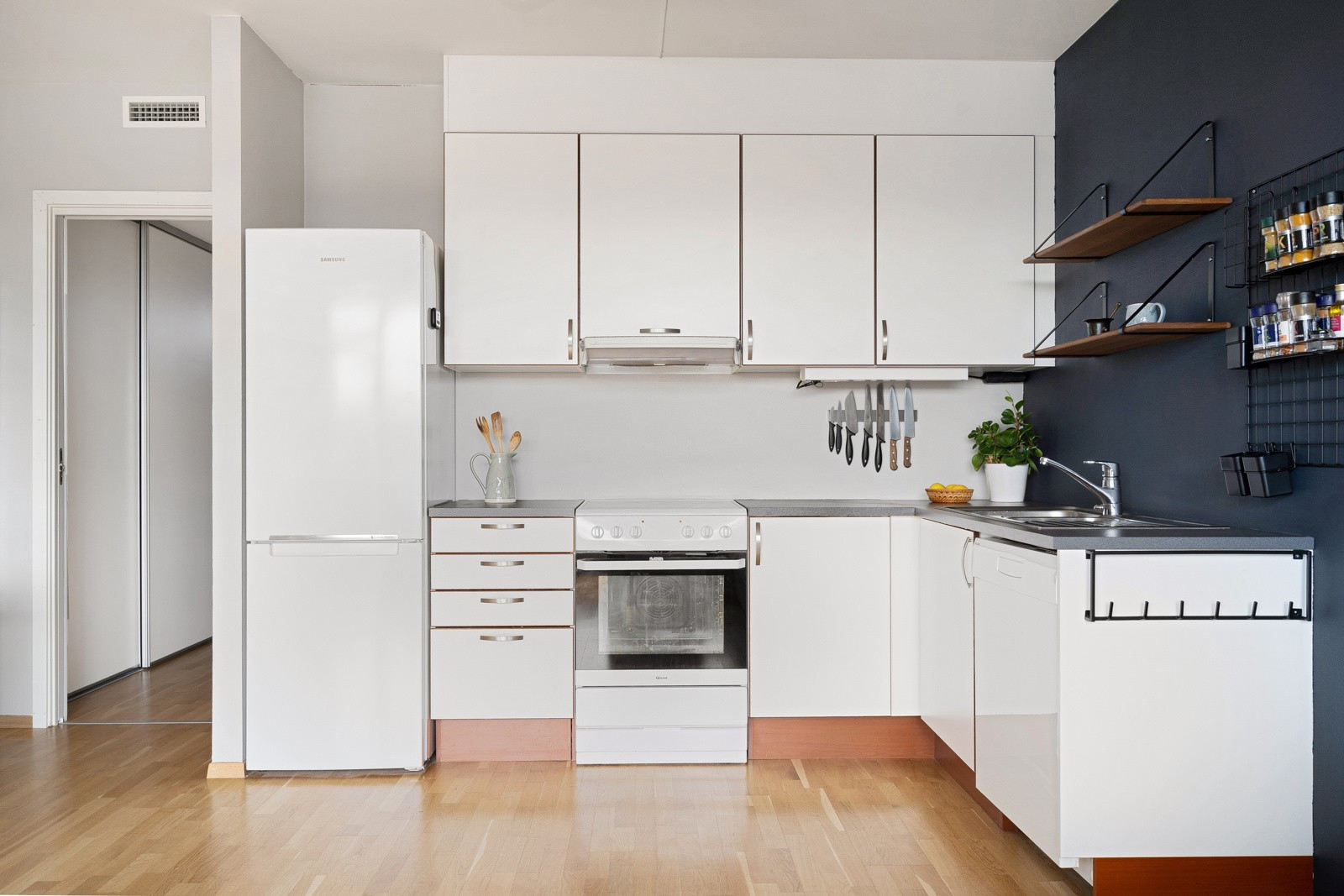 Lyst kjøkken med glatte fronter og rikelig med oppbevaringsplass i over- og underskap.