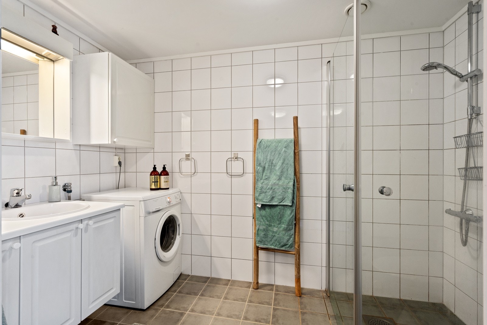 Lekkert, flislagt bad på 5 m² med innfellbare dusjdører, opplegg for vaskemaskin og varmekabler i gulv Galleribilde