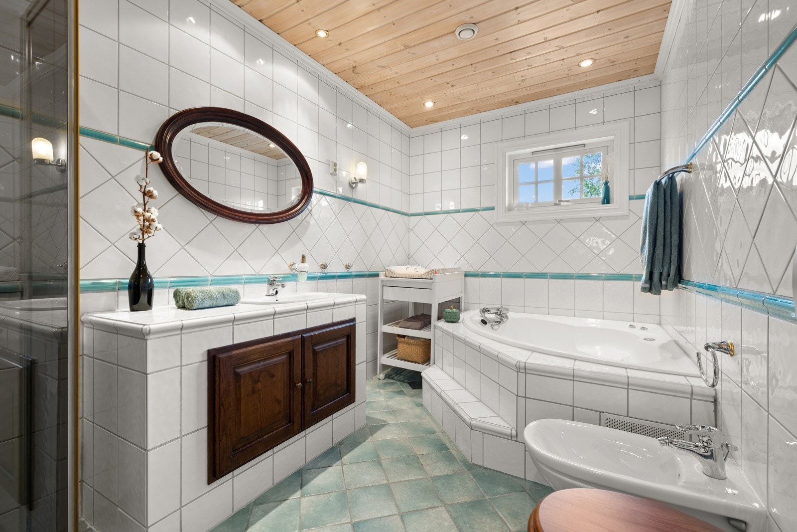 Flislagt badeværelse med gulvvarme. Badet byr på badekar, dusjnisje, innfliset servant samt klosett og bide. Galleribilde