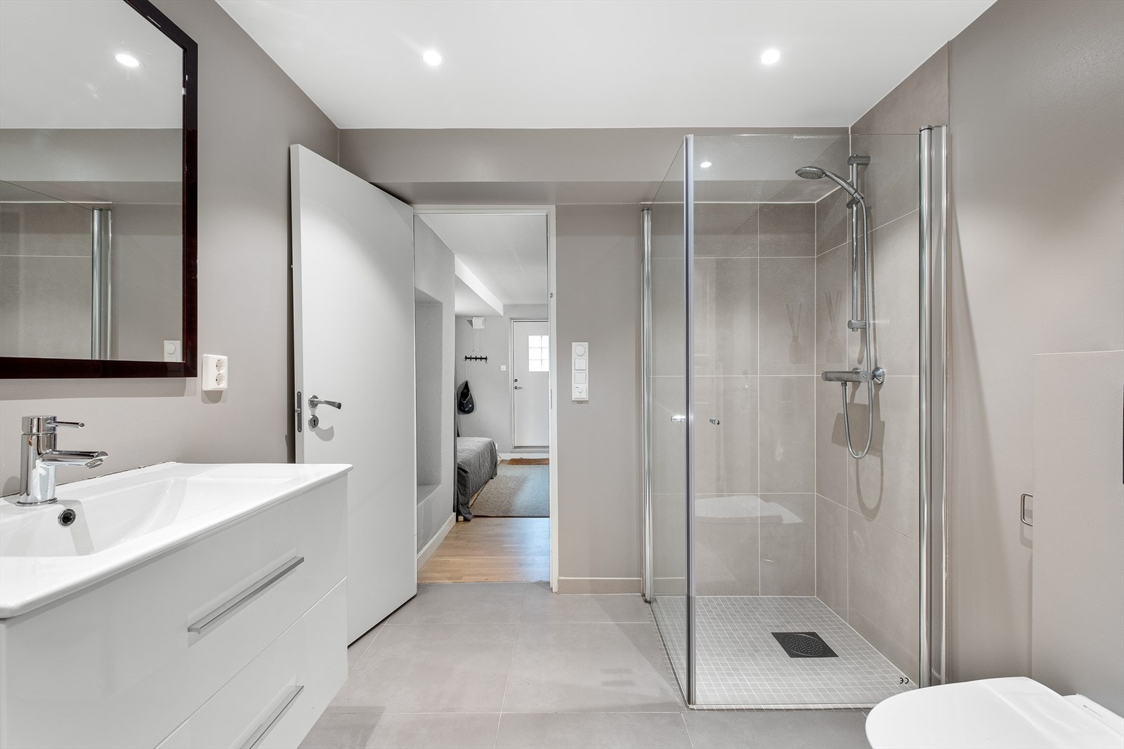 Lekker og moderne bad tilhørende utleiedel er utstyrt og innredet med servantskap med skuffer og heldekkende servant. Videre har badet dusjhjørne og vegghengt toalett. Galleribilde