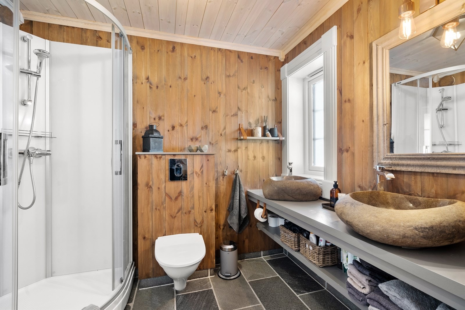 Badet har toalett, dusjkabinett og to vasker. Galleribilde