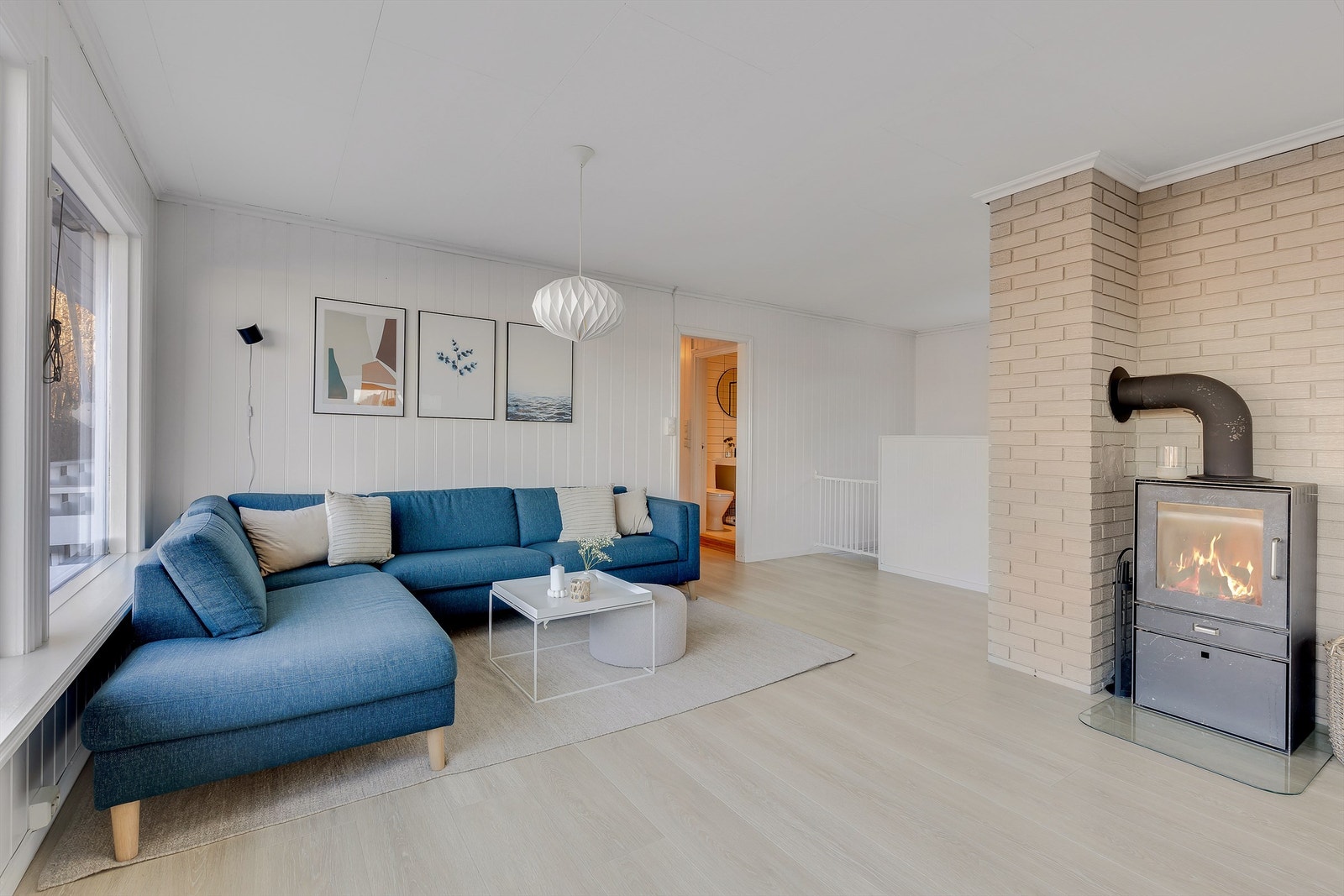 Sofaen vender mot de store stuevinduene med utsikt utover sjøen og mot peisovnen. Galleribilde