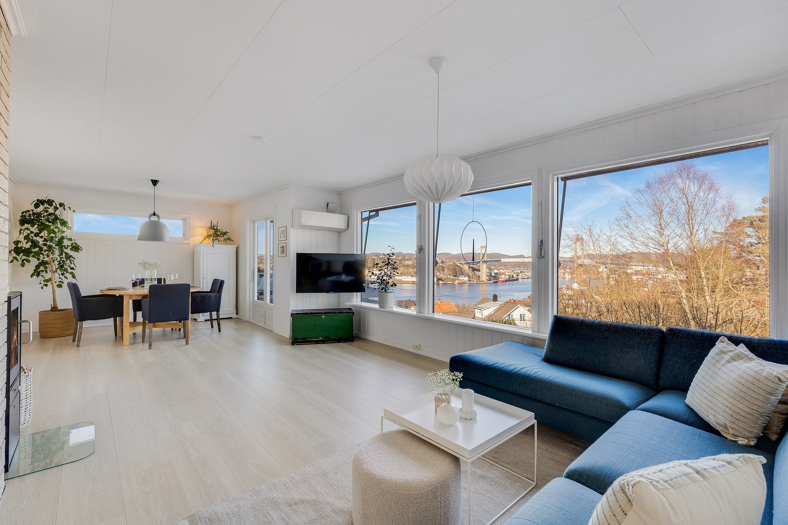 STUEN ER LYS og åpen. de store vinduene slipper inn rikelig med naturlig lys. Et tre i hjørnet bak spisegruppen gir god atmosfære i rommet. Galleribilde