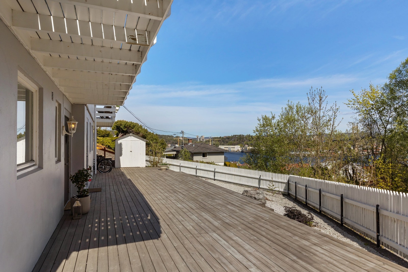 Terrasse ved inngangsparti med enkelt redskapshus rett frem. Galleribilde