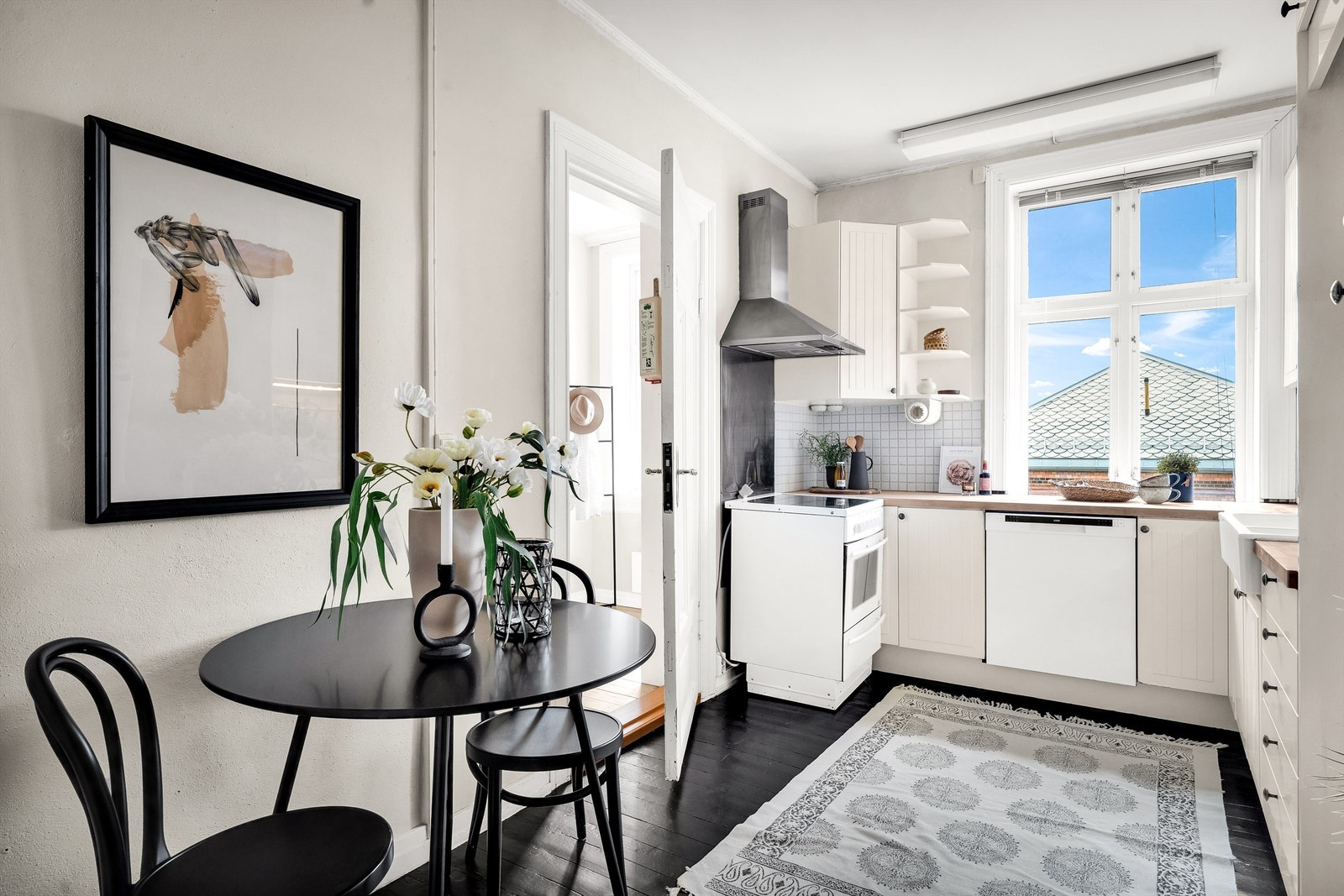 Separat kjøkken med tidløs innredning og plass til et lite spisebord. Kjøkkeninnredningen har hvite skapfronter og laminat benkeplater. Galleribilde