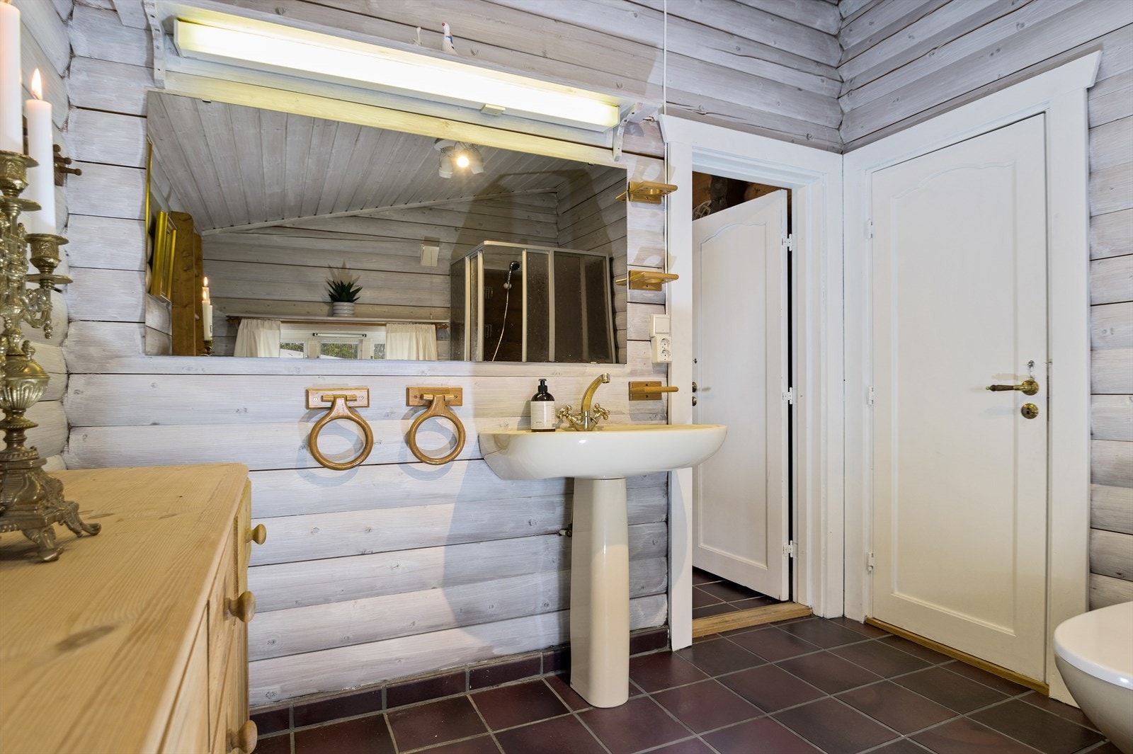 Baderommet er innredet med dusjkabinett og badekar, servant og gulvmontert toalett. Dusjkabinett og badekar hindrer at vegger og gulv eksponeres direkte for vann når man dusjer. Galleribilde