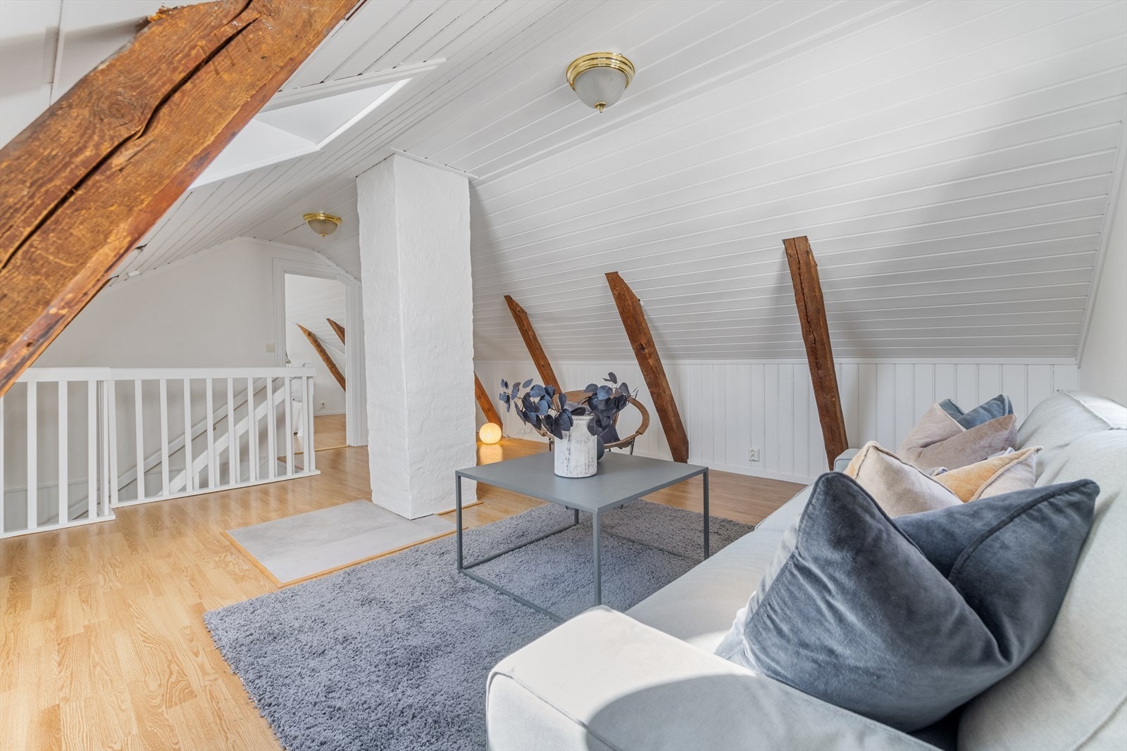 Stuen er et koselig rom med skråtak og synlige takbjelker Galleribilde