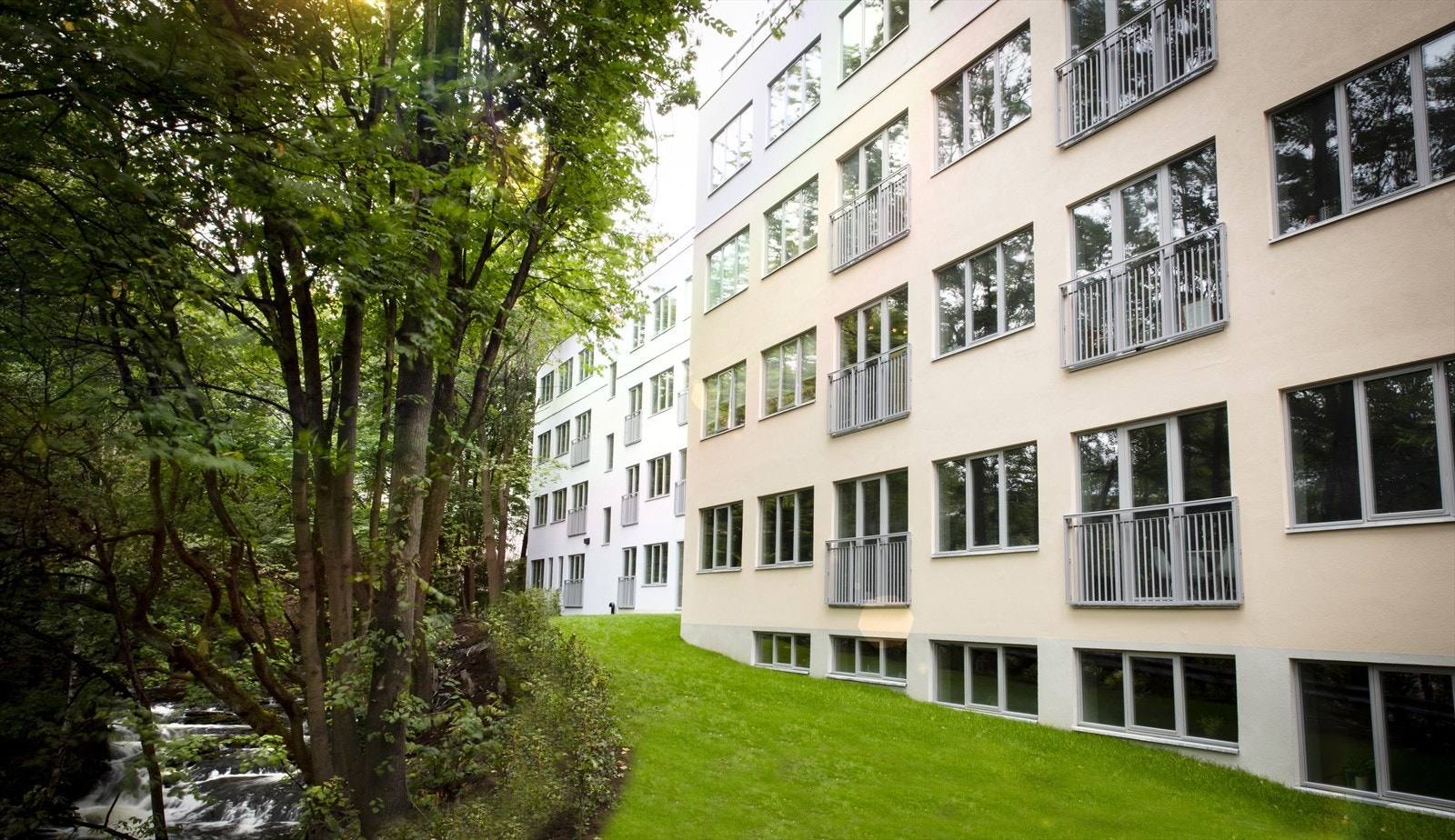 Moderne fasade og gressplen mellom Akerselva og bygget. Galleribilde