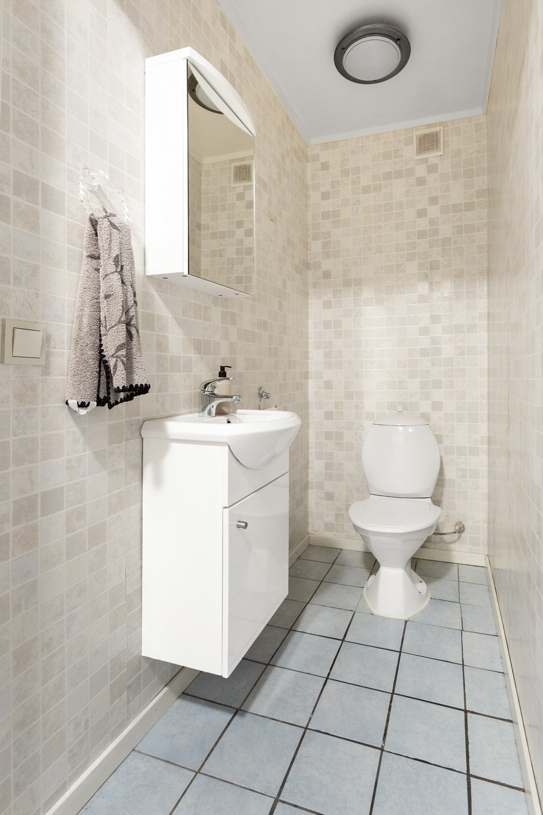 Toalettrom med fliser på gulv og vinyltapet på vegger. Galleribilde