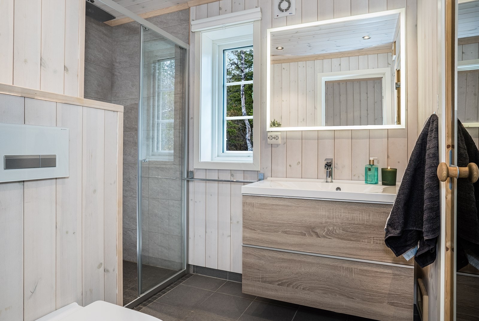 Hovedbad med dusjnisje, veggmontert klosett, baderomsinnredning i heltre og direkte adkomst til badstue. Galleribilde