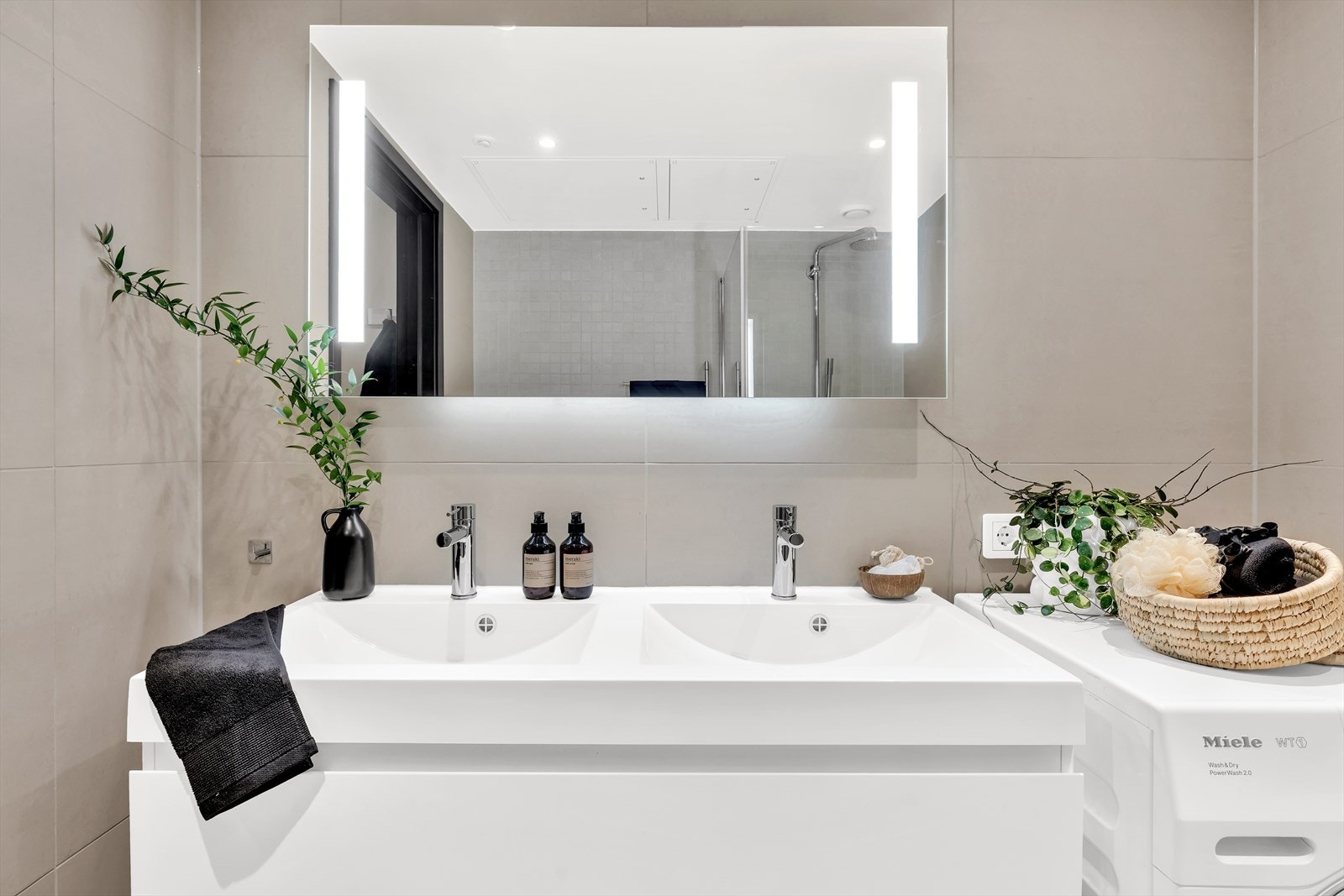 Det er vegghengt toalett, dusjhjørne med innfellbare glassdører, speil med belysning og heldekkende servant med underliggende skuffeseksjoner fra HTH. Galleribilde