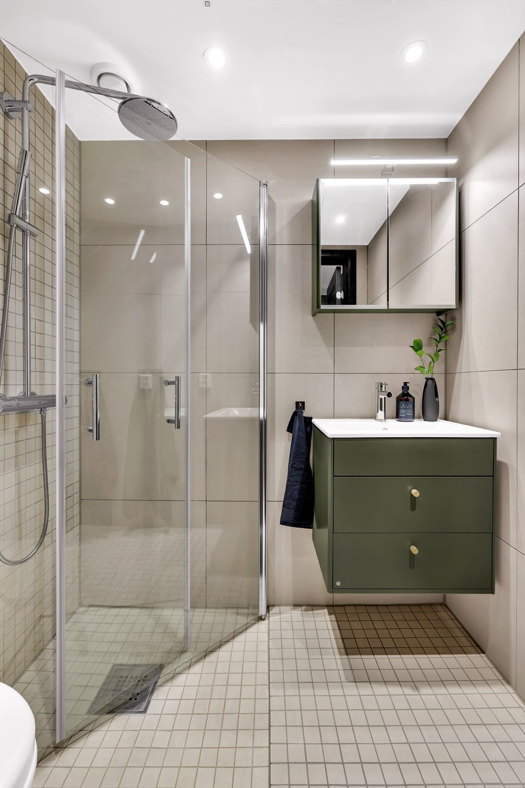 Det er innredet med servant med underliggende skuffeseksjoner fra HTH, dusjhjørne med innfellbare dusjdører og vegghengt toalett. Her er det speilskap med oppbevaring og lys, downlights i himling og vannbåren gulvvarme. Galleribilde