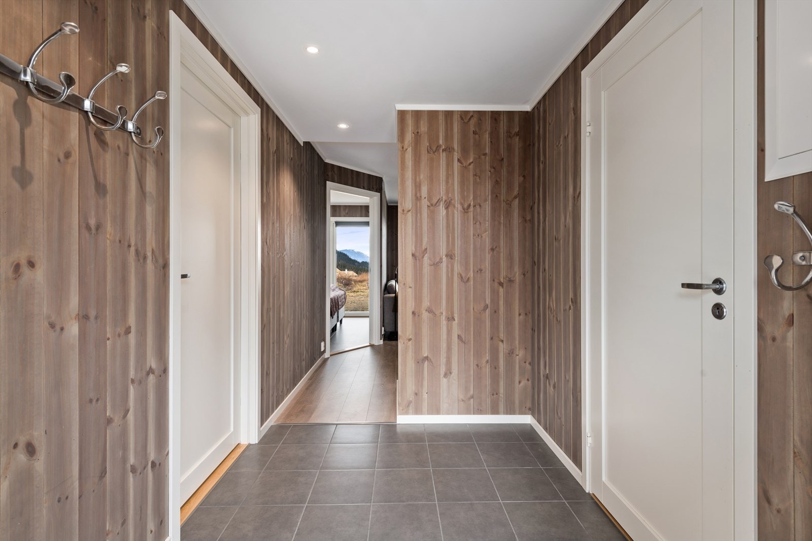 Velkommen inn. Romslig flislagt entré med tilgang til ett av soverommene. Galleribilde