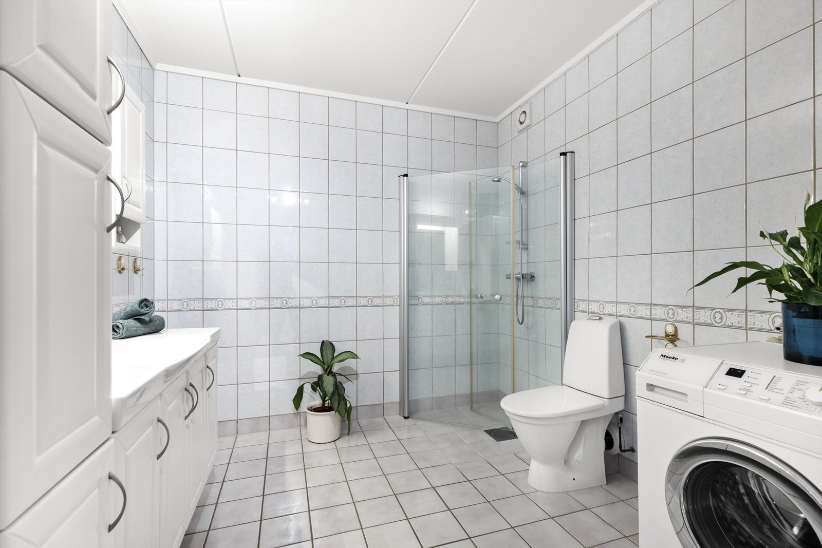 Innholdsrikt bad med blant annet innfellbare dusjdører, mekanisk avtrekk, servantskap og wc Galleribilde