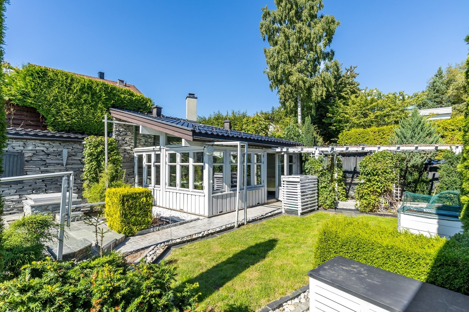 Bakhagen er pent opparbeidet med plen, planter og busker Galleribilde