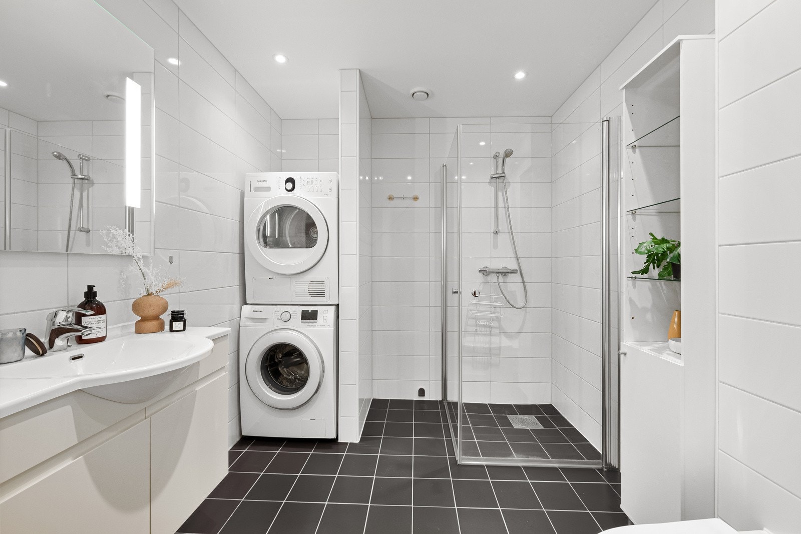 Leiligheten har et innbydende, flislagt bad med varme i gulvet og downlights i himling. Gulvet har mørke fliser og veggene hvite. Galleribilde