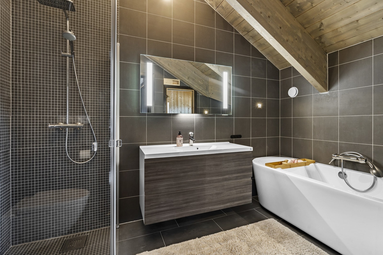 Badet i forbindelse med hovedsoverommet. Servant med skuffer under, badekar, dusjhjørne, wc og badstue. Galleribilde