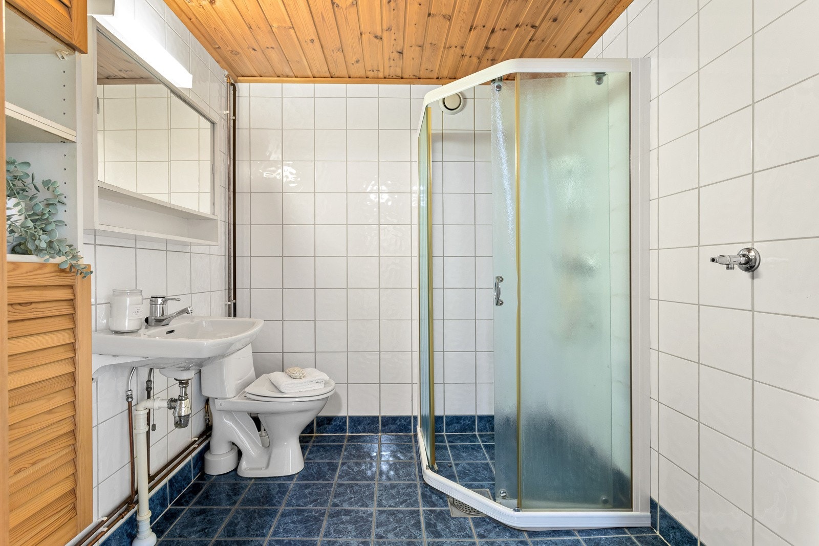 Flislagt bad med varme i gulv fra slutten av 90-tallet. Dusj, servant i helstøpt plate, klosett og opplegg for vaskemaskin. Galleribilde