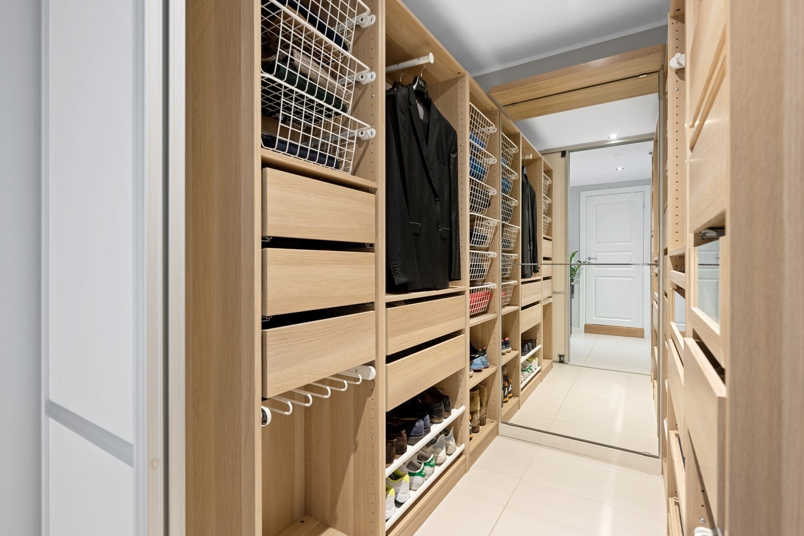 Det er direkte tilgang til et stort, praktisk walk-in-closet som er pent innredet med åpne garderobeløsninger på begge sider av veggen Galleribilde