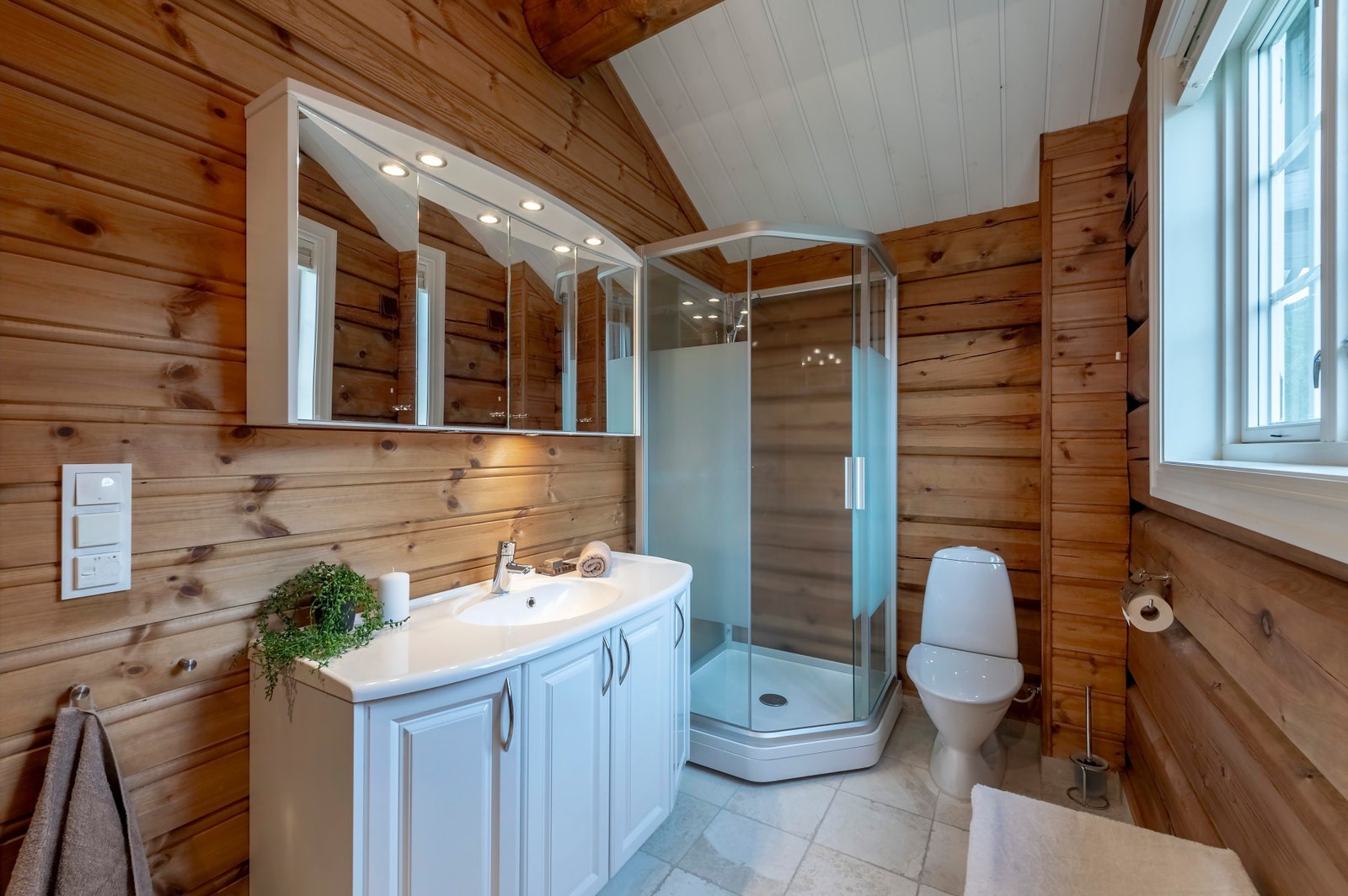 Bad i 2. etasjen på 6 kvm med panel og laftet tømmer. Himling/innvendig tak har malt panel. Galleribilde