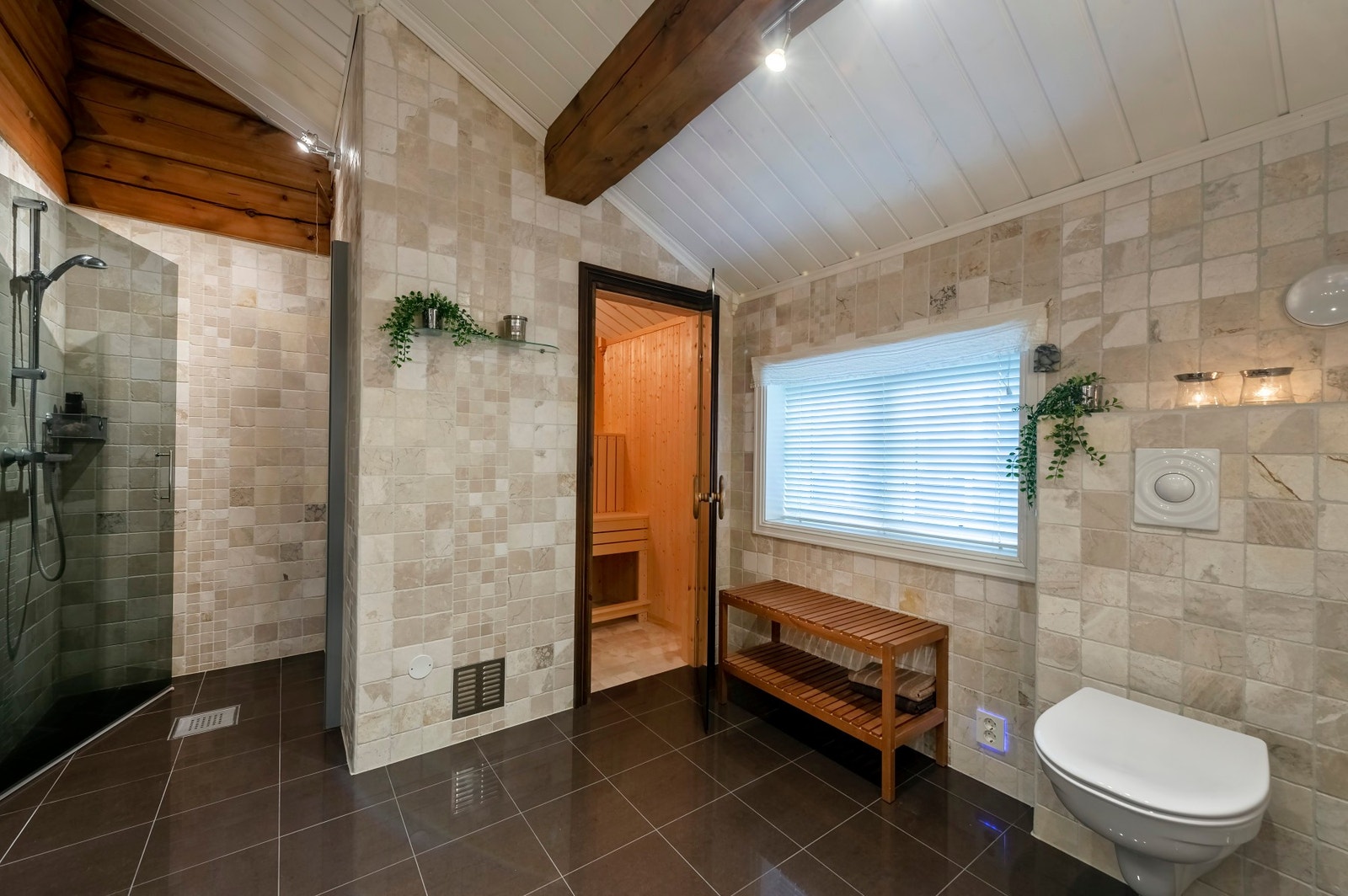 Badet har flis og laftet tømmer på vegger. Himling/innvendig tak har malt panel. Galleribilde