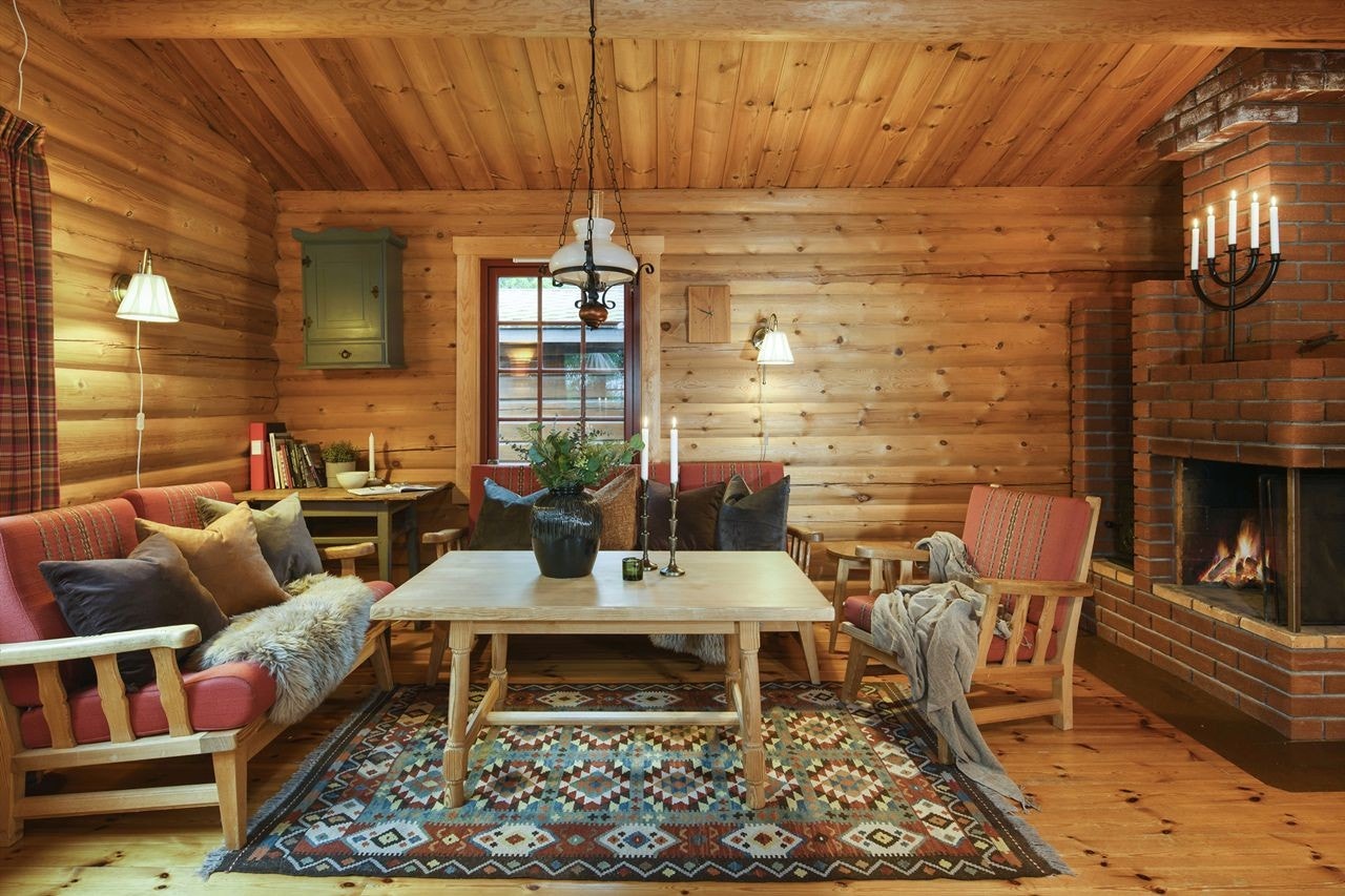 En trivelig sofakrok framfor peisen. Ubehandlede tømmervegger, gulv og tak i tre Galleribilde