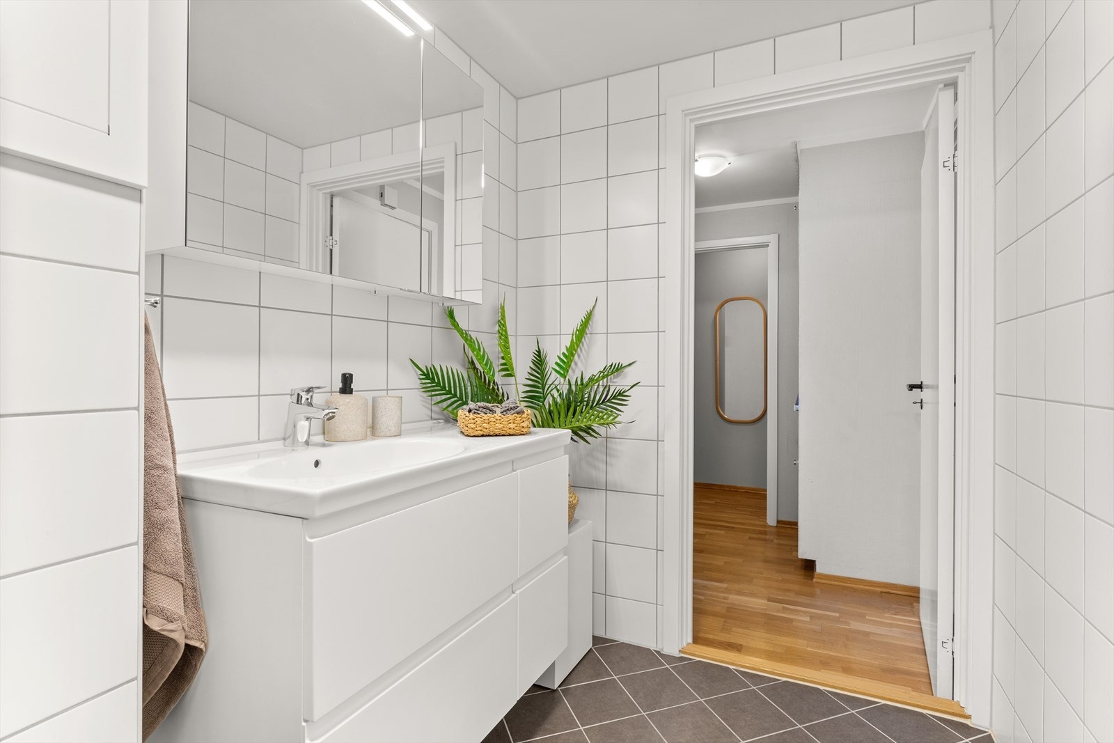 Bad består av inn-utadslående dusjvegger, servant m/underskap, veggmontert toalett, overskap med speilfronter og opplegg for vaskemaskin. Varmekabel i gulv. Galleribilde