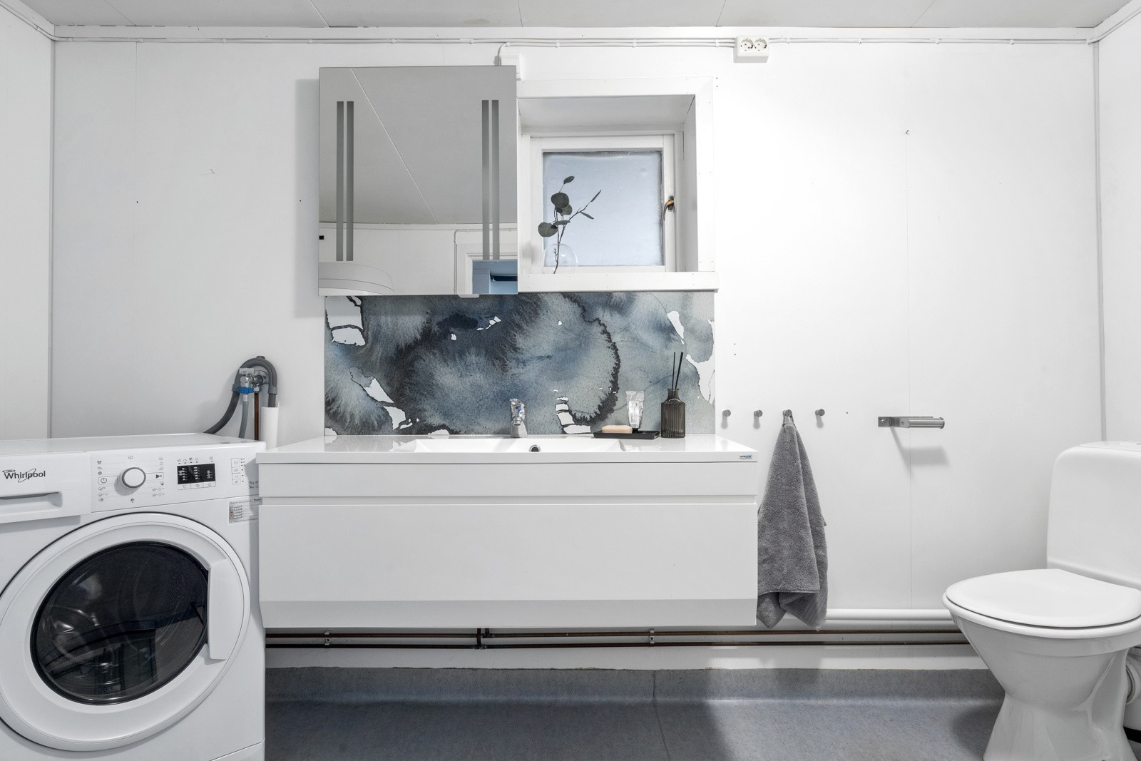 Badet er innredet med lys baderomsinnredning, toalett, dusjkabinett. Opplegg for vaskemaskin