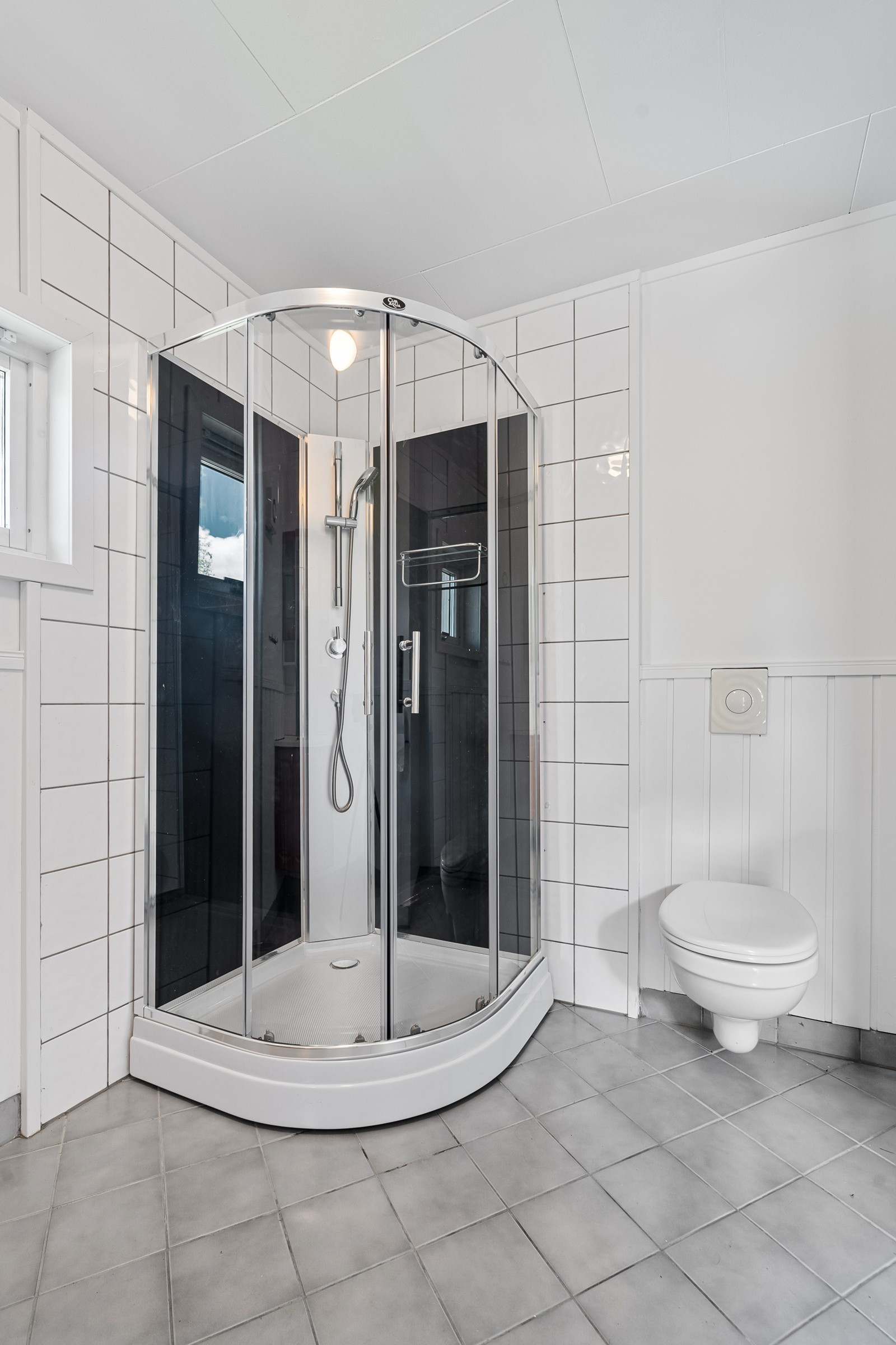 På badet er det dusjkabiunett og vegghengt toalett.