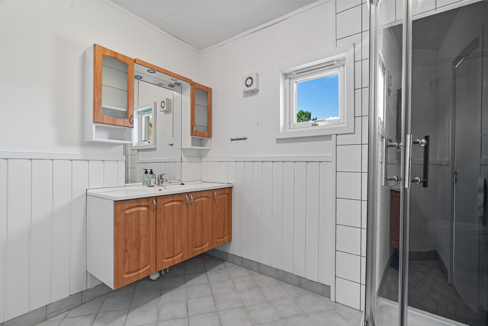 Badet er renovert i 2005 og har flislagt gulv med gulvvarme og har baderomsinnredning med speil og overskap.