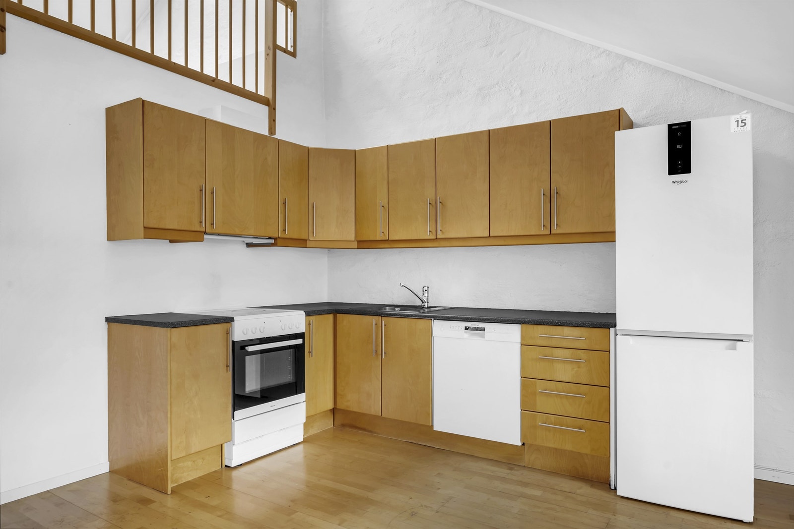 Videre er kjøkkenet utstyrt med belysning under overskap og laminat benkeplate med nedfelt kum i rustfritt stål, frittstående kjøleskap, oppvaskmaskin og komfyr. Galleribilde