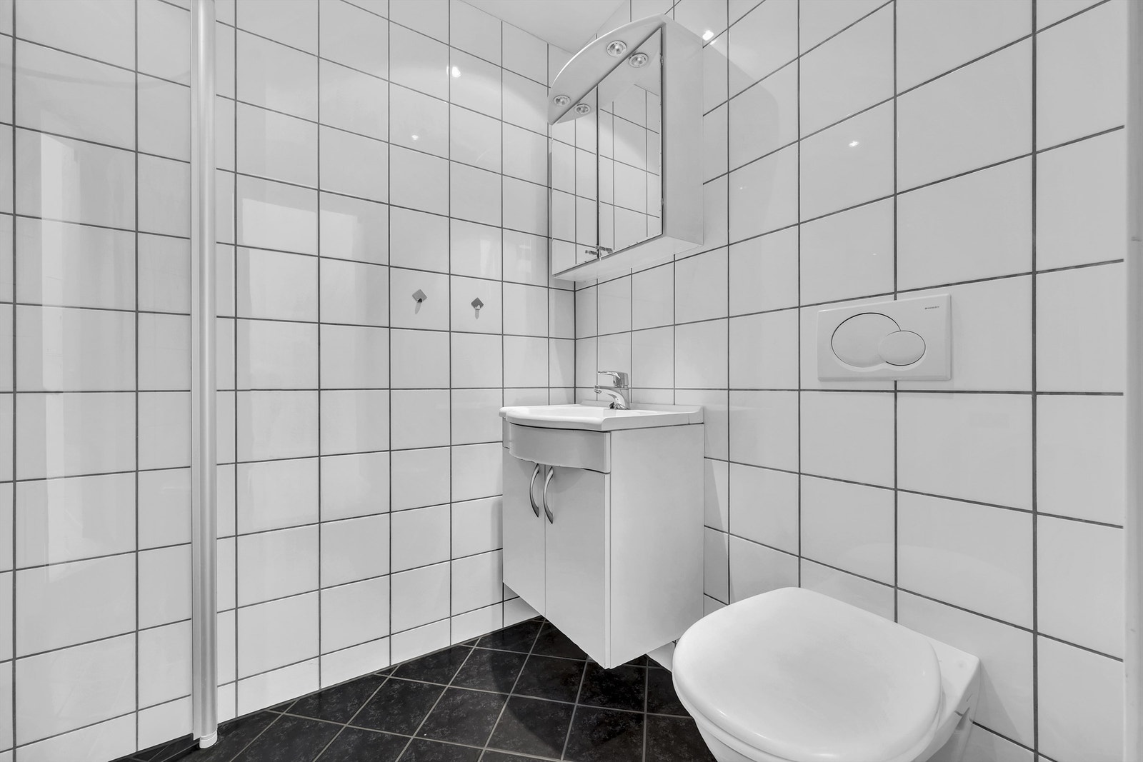 Baderommet er utstyrt med vegghengt servantskap med dører, ovenpåliggende servant med ett-greps armatur, speilskap over servanten med belysning og vegghengt toalett. Galleribilde