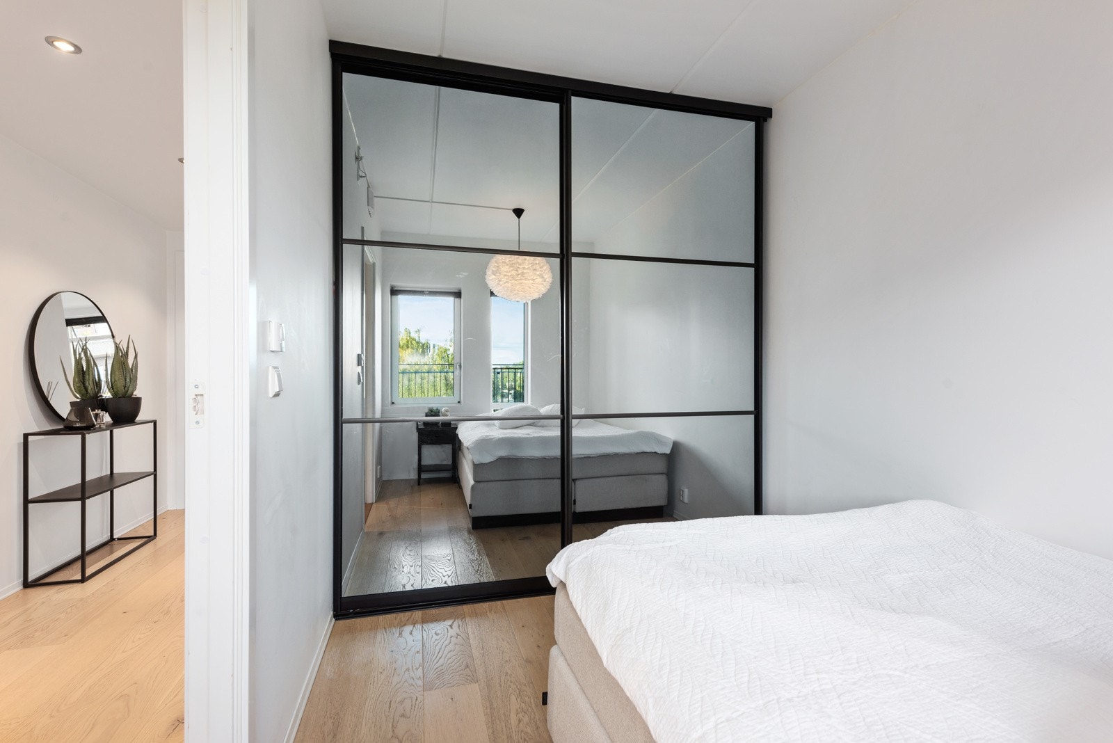 Soverommet er innredet med skyvedørsgarderobe med tidsriktig uttrykk med speil og sorte sprosser Galleribilde