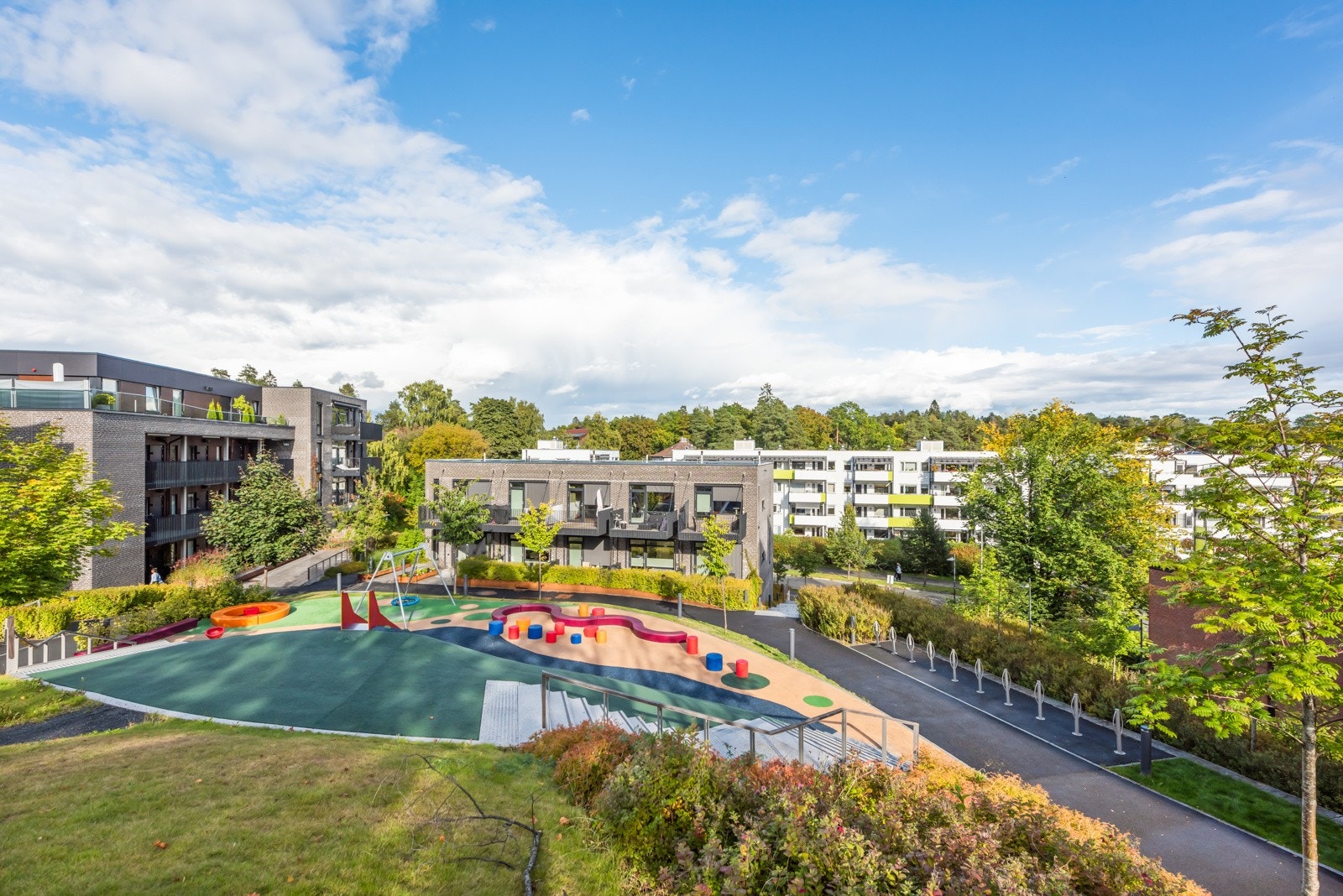 Fellestomten har asfalterte internveier og er omkranset av frodig beplantning Galleribilde