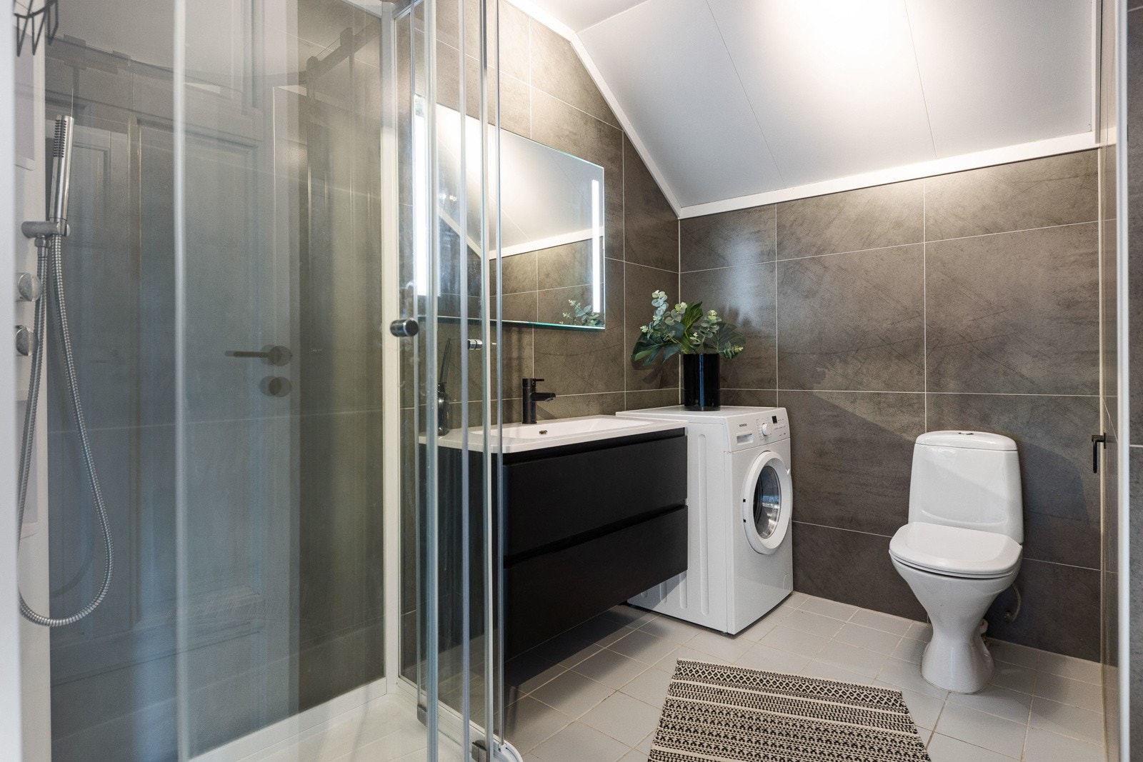 Badet er utstyrt med dusjkabinett, gulvvarme og opplegg for vaskemaskin. Galleribilde