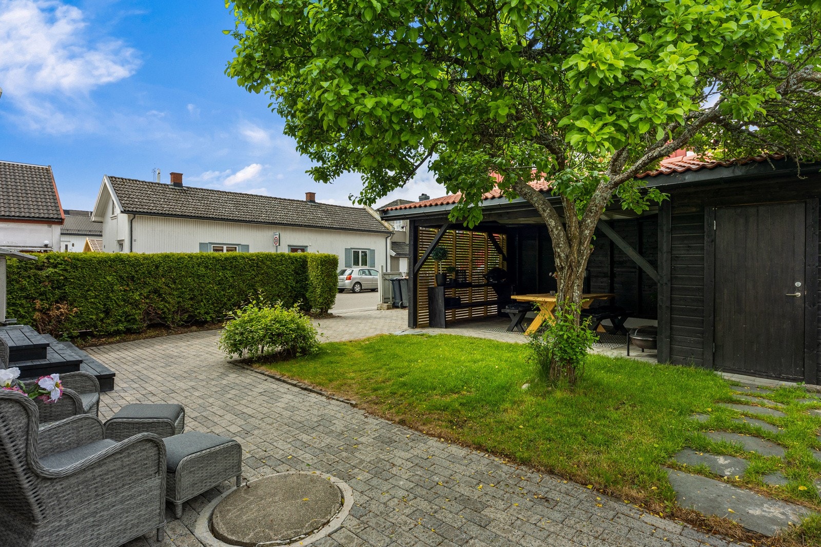 Hagen er pent opparbeidet med gressplen, hekk, gjerde og et stort tre. Galleribilde