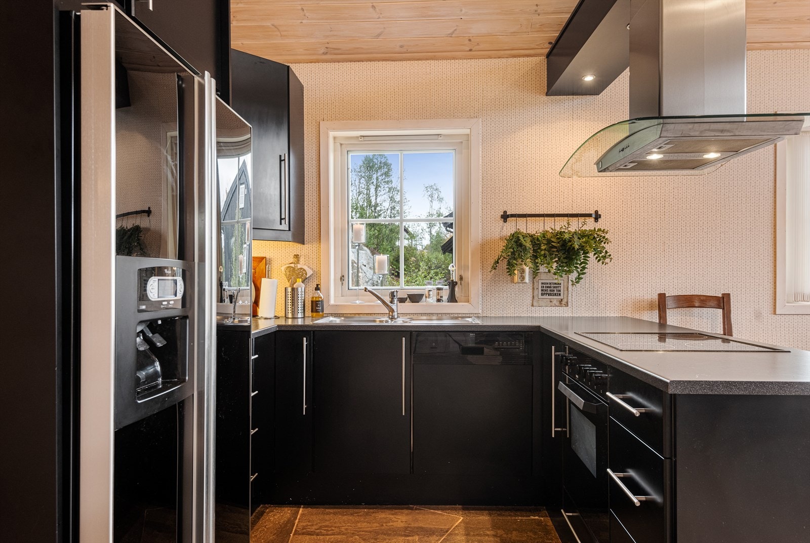 Kjøkkeninnredning i mørk utførelse med integrert platetopp, oppvaskmaskin og komfyr Galleribilde