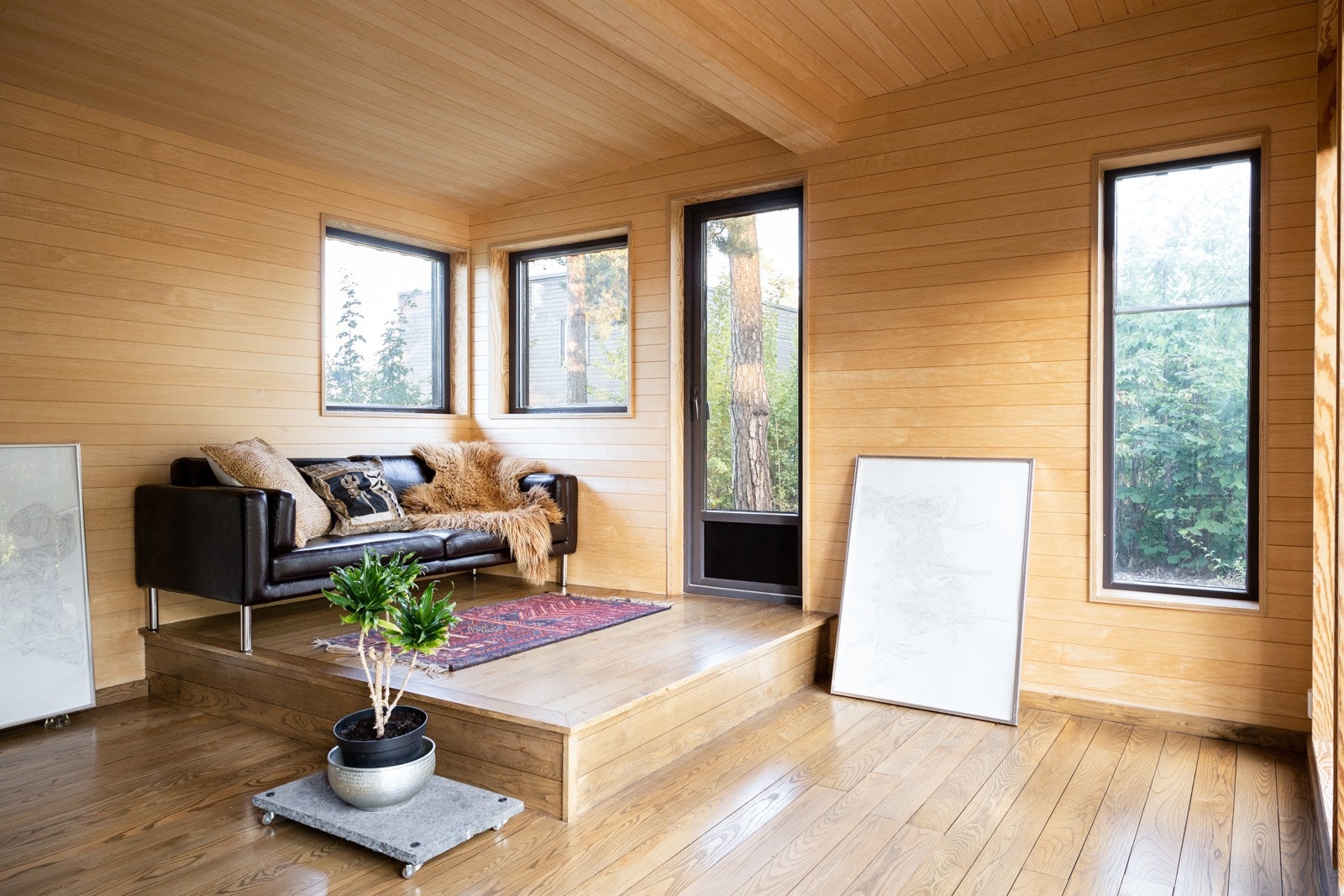 Stue med overflater kledd i trepanel i svartor og treplater på vegg og slitesterkt panel i ask på gulv. Galleribilde