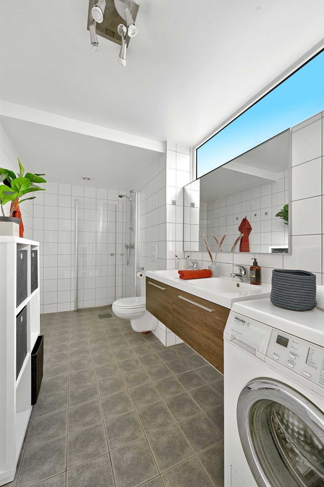 Kombinert bad/vaskerom med toalett, servantskap med doble vasker, dusjhjørne og opplegg for vaskemaskin Galleribilde