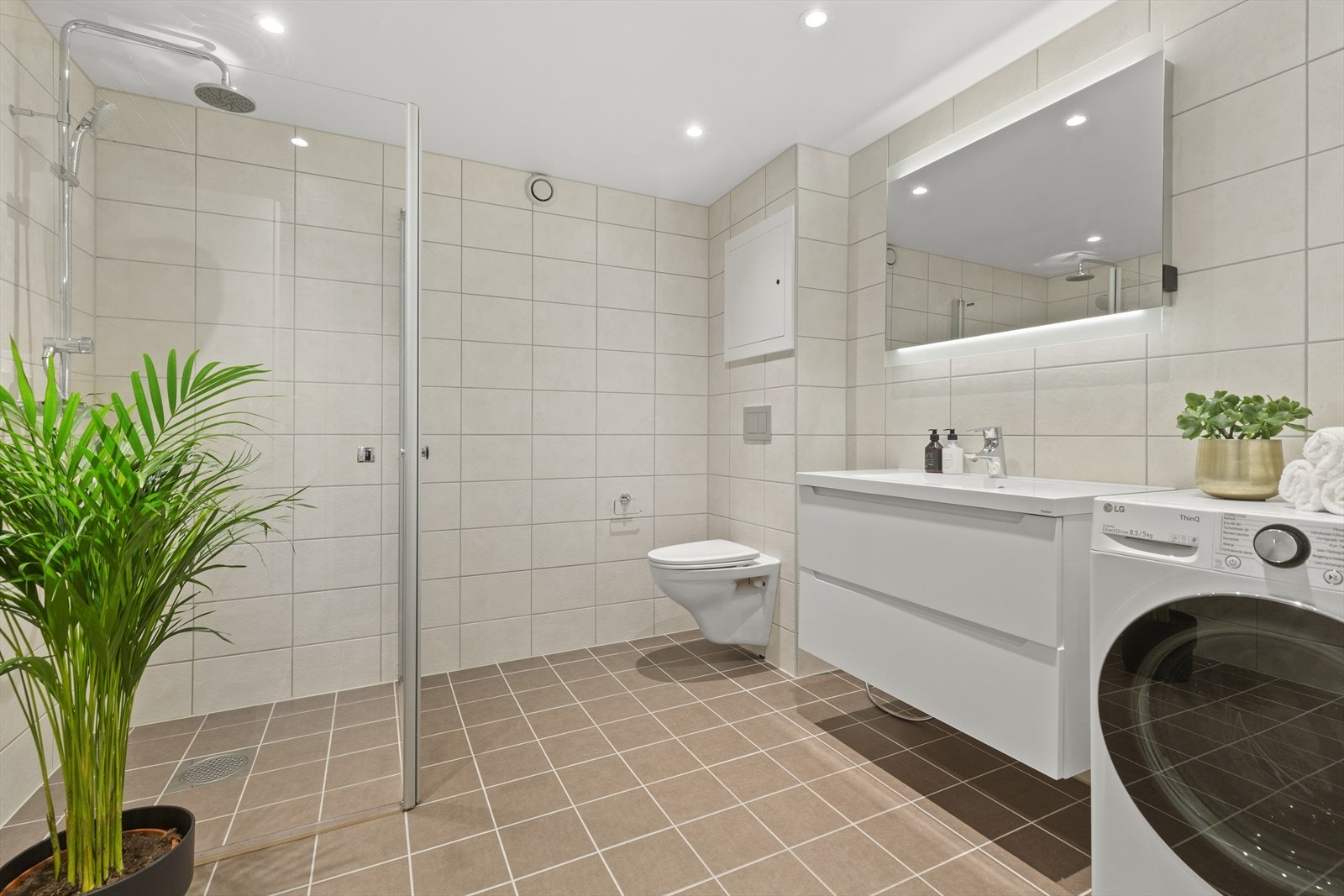 Flislagt gulv og gulvvarme. Bad består av inn-utadslående dusjvegger, servant m/underskap, veggmontert toalett, overskap med speilfronter og opplegg for vaskemaskin. Galleribilde