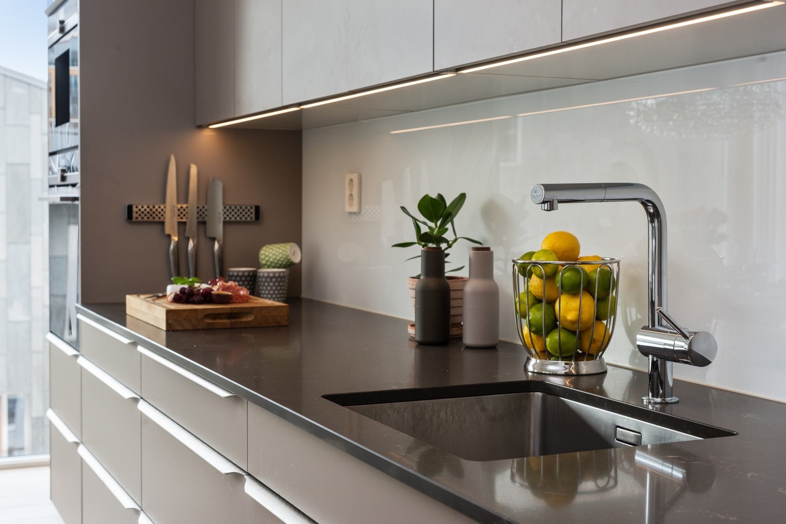 Stor kjøkkenbenk med glassplate (mellom benk og skap), samt belysning under kjøkkenskap Galleribilde