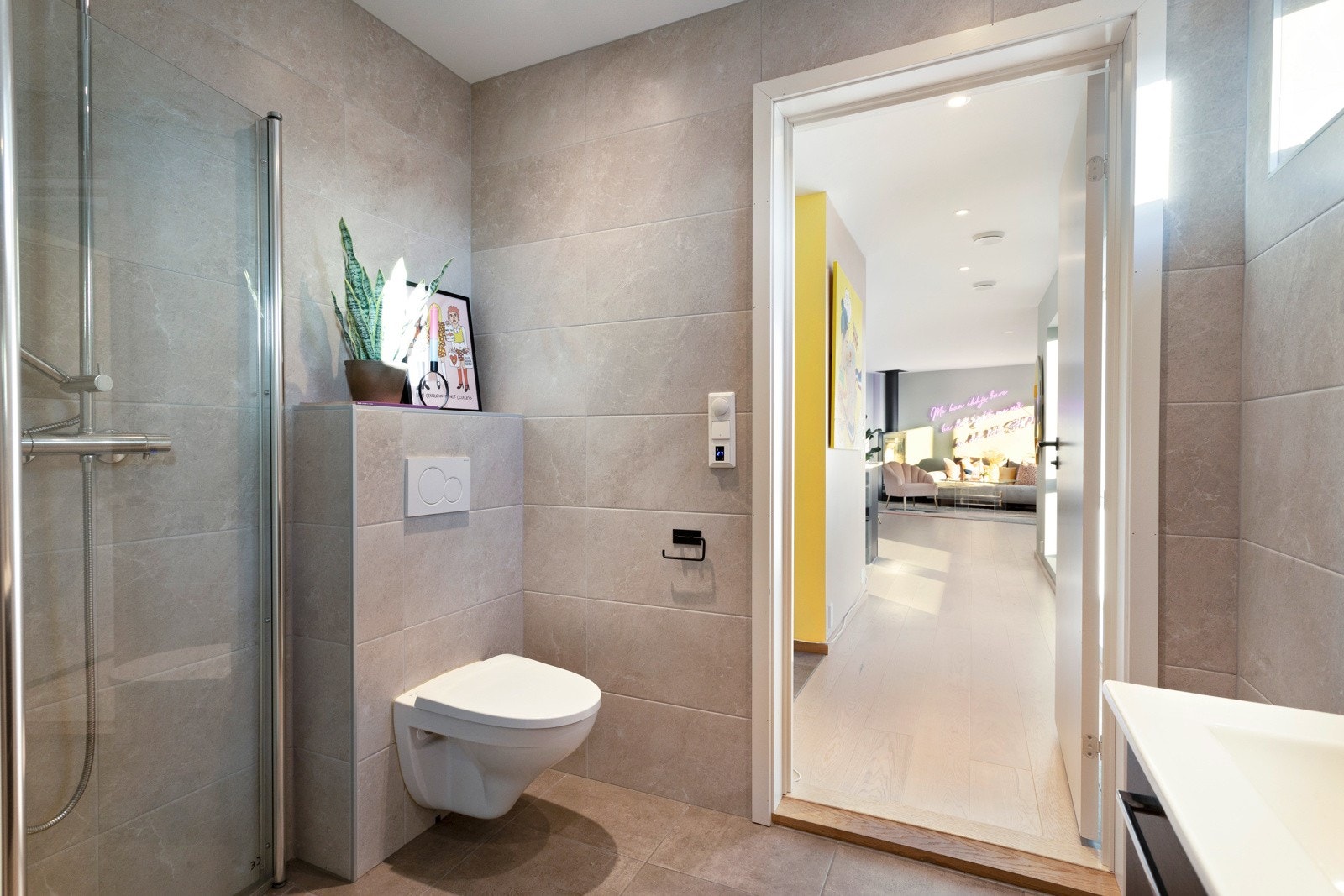 Pent flislagt bad med dusjhjørne og vegghengt toalett. Galleribilde