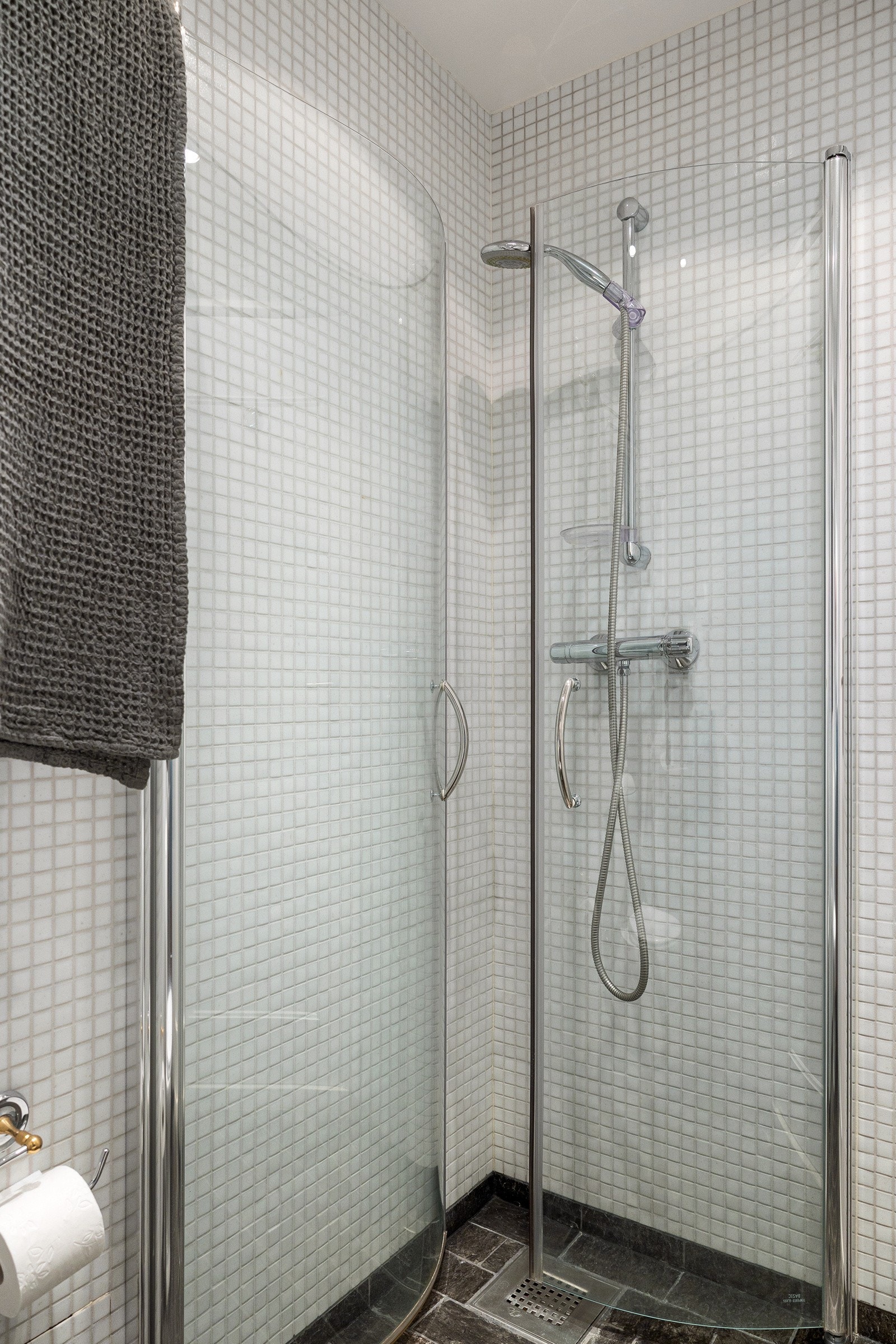 Det lille badet har dusj med plassbesparende, innfellbare glassdører. Galleribilde