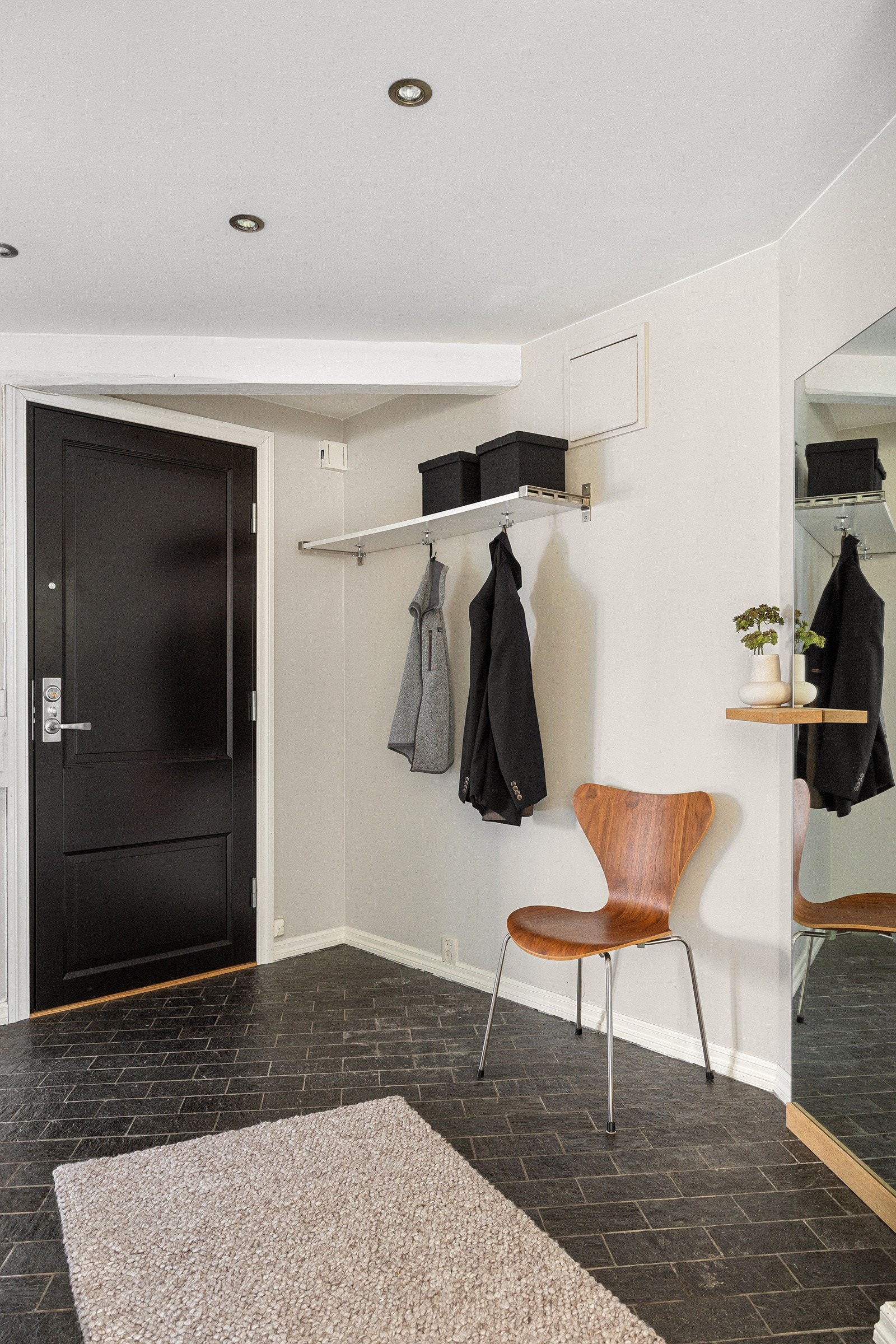 Entreen har adkomst til stue, ett av soverommene og det minste badet. Entreen har fliser på gulv, sort ytterdør og dørcalling ved siden av døren. Galleribilde