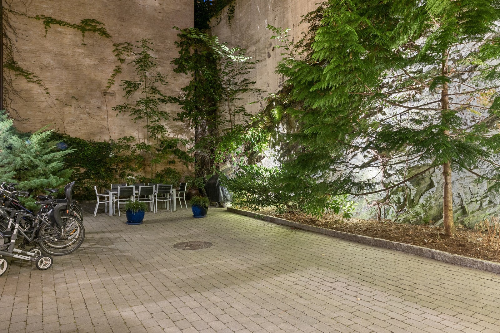 Bakgården er pent opparbeidet med brostein, beplanting, trær og bed. Det er felles grill i bakgård. Galleribilde