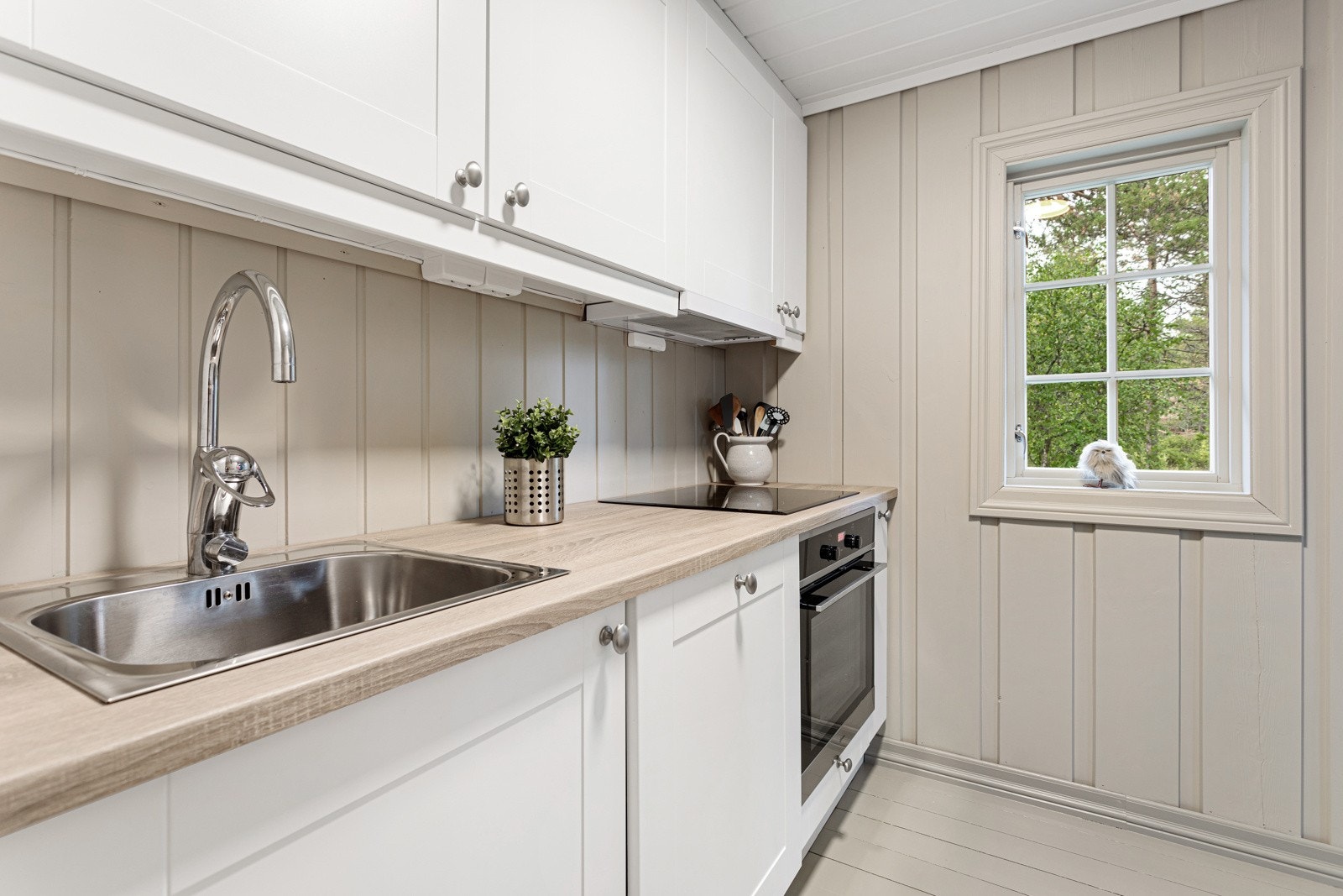 Kjøkkenet inneholder hvitevarer som komfyr, platetopp og helintegrert kjøleskap med frysedel. Galleribilde