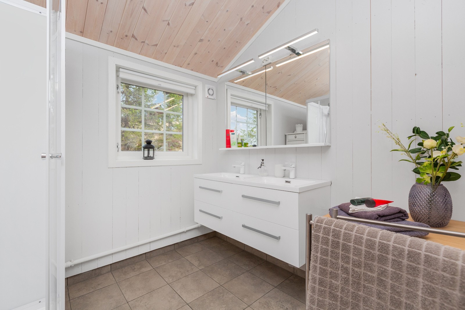 Bad med flislagt gulv med varmekabler, innredet med dusjkabinet og pen innredning. Galleribilde