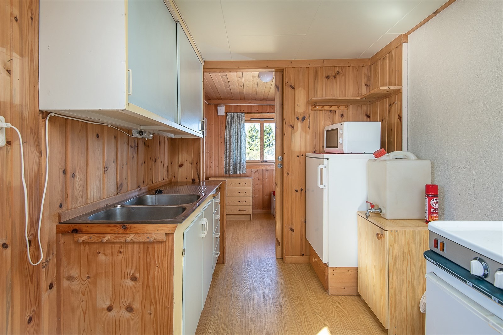 Enkelt kjøkken der innredning er i malt utførelse. Over-og underskap. Oppvaskkum. Plass til kjøleskap. Galleribilde