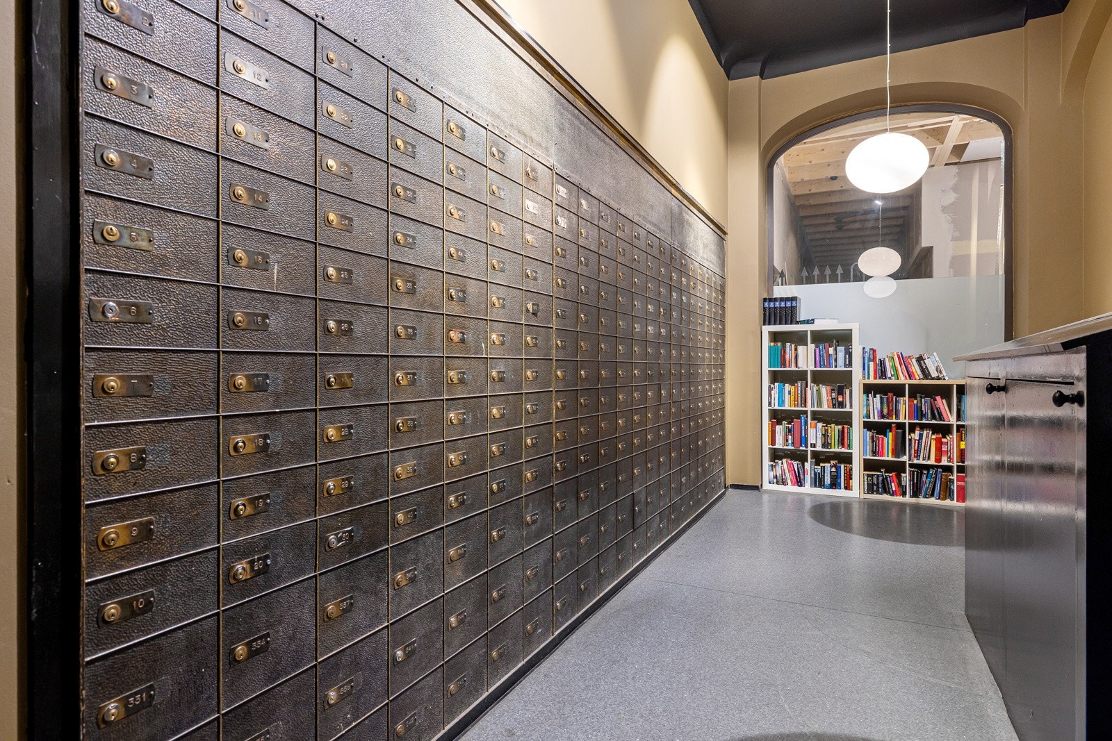 Gamle bankbokser fungerer som gårdens postkasser i dag, med delebibliotek for sameiet. Galleribilde